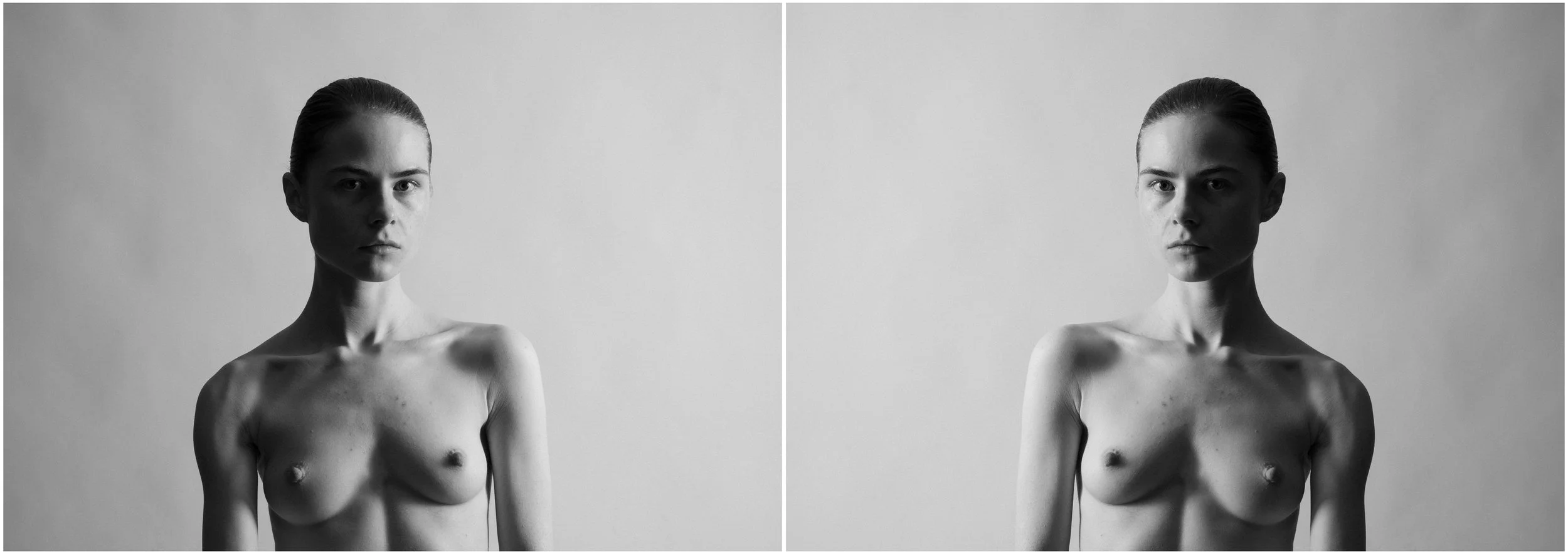 A black and white mirror-reflection portrait of a young woman. Her hair is tight up. She is looking into the camera. Very strong shadows and contrasts.
