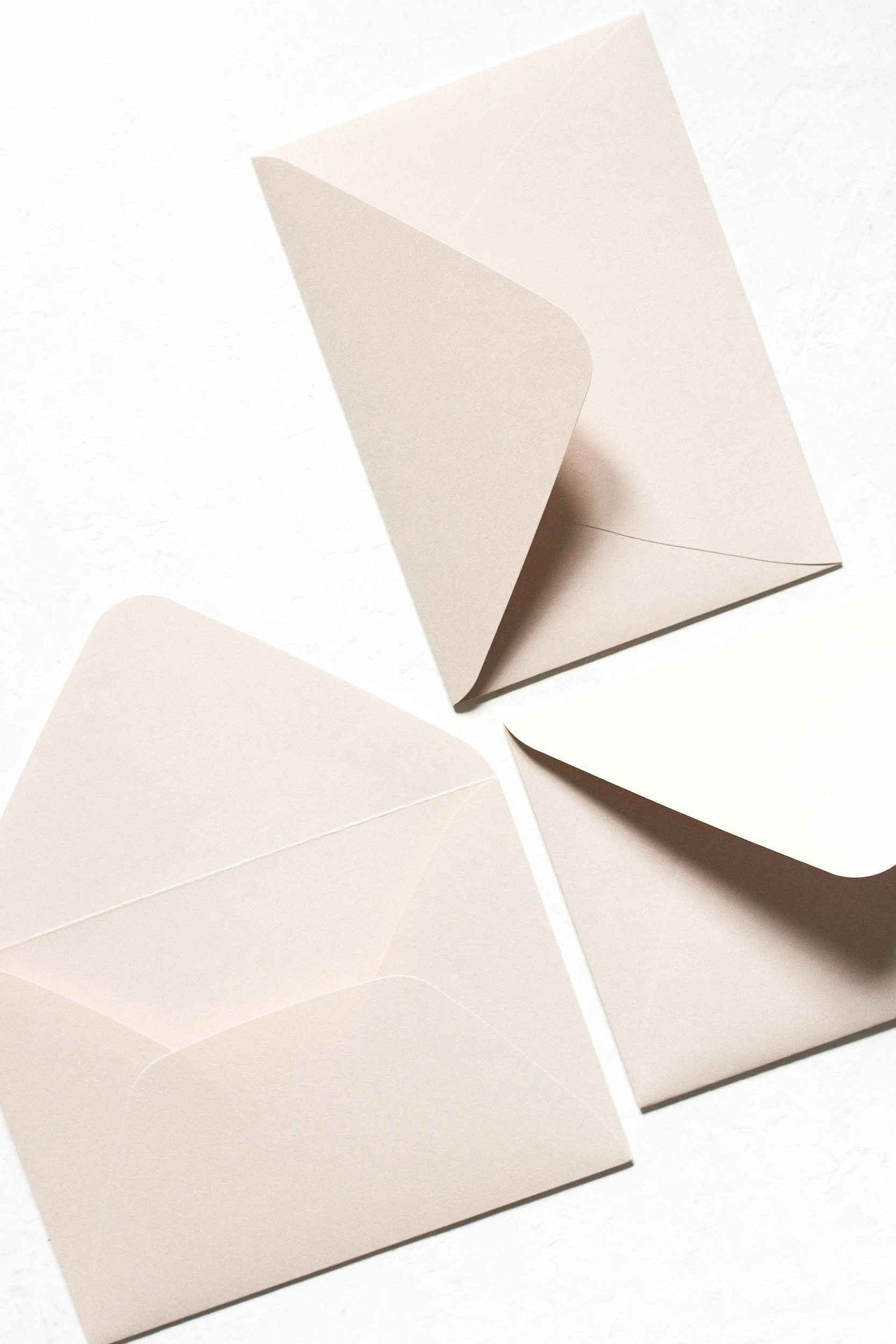Three blank, unfolded white envelopes on a white surface.