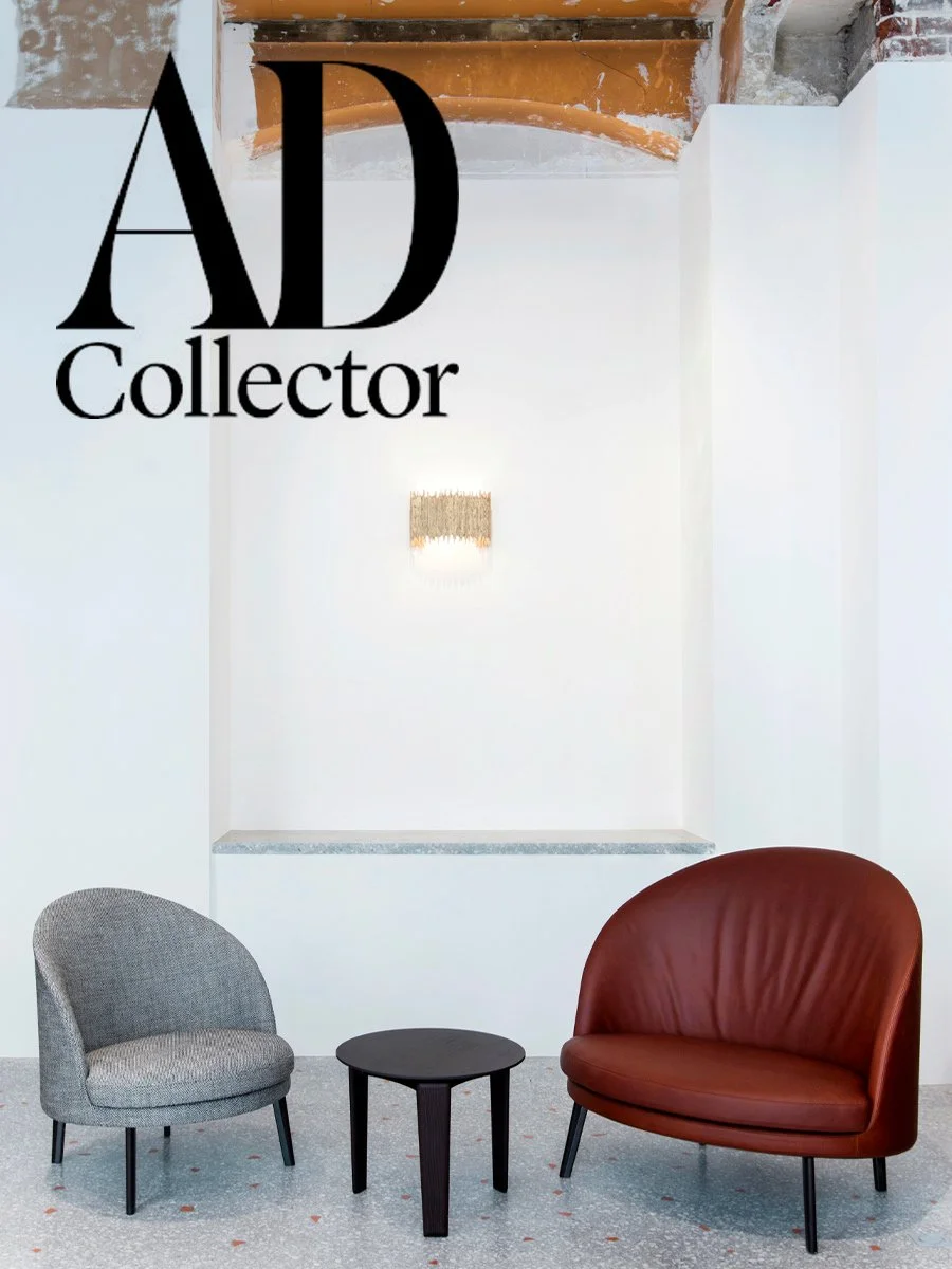 Deux fauteuils, un gris et un marron, avec une petite table ronde noire entre eux, dans une pièce blanche avec un mur blanc en arrière-plan.