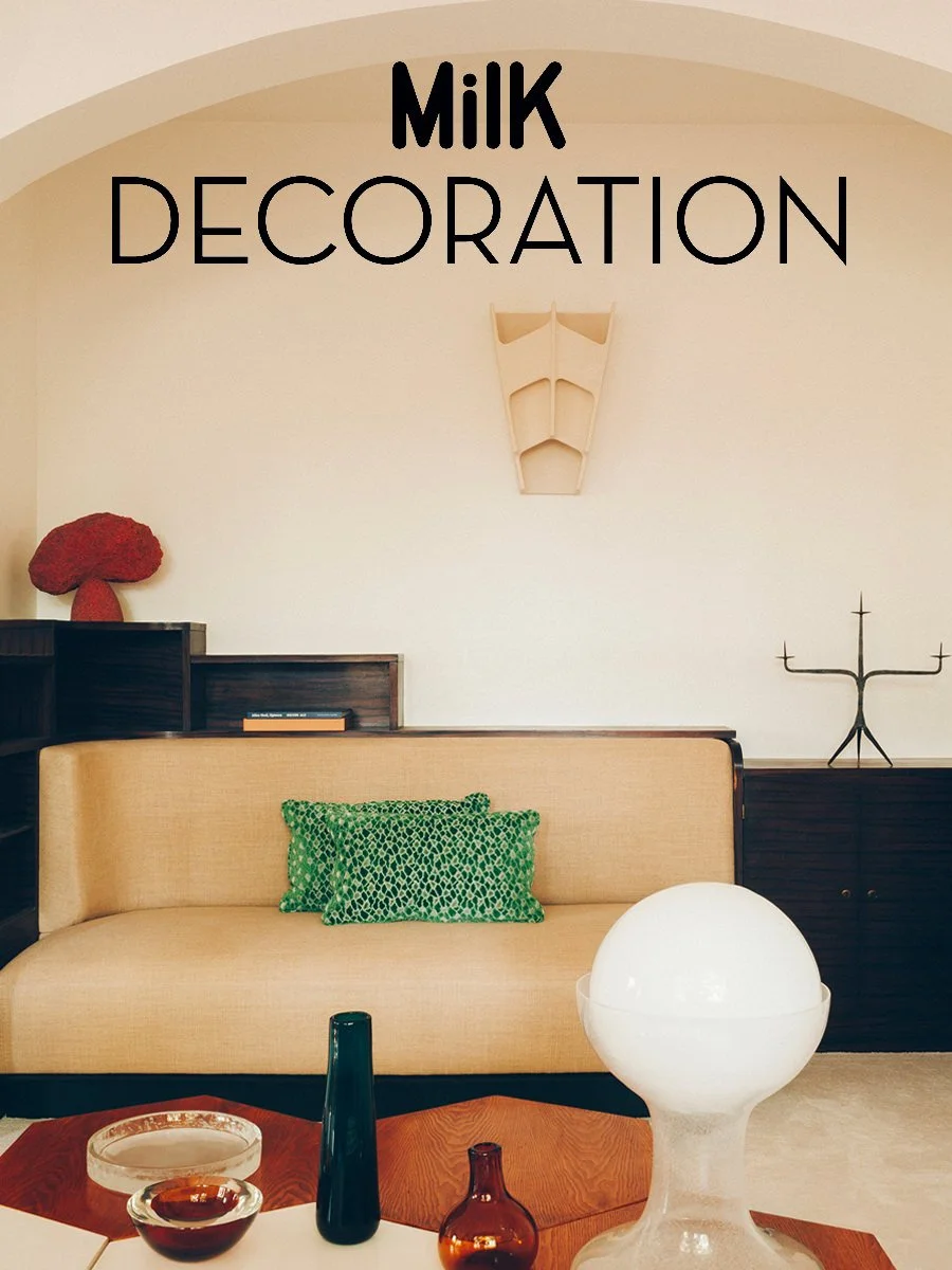Intérieur de salon avec canapé beige, coussins verts, décor en bois, sculpture en verre blanc, objets en céramique et décoration sur les étagères