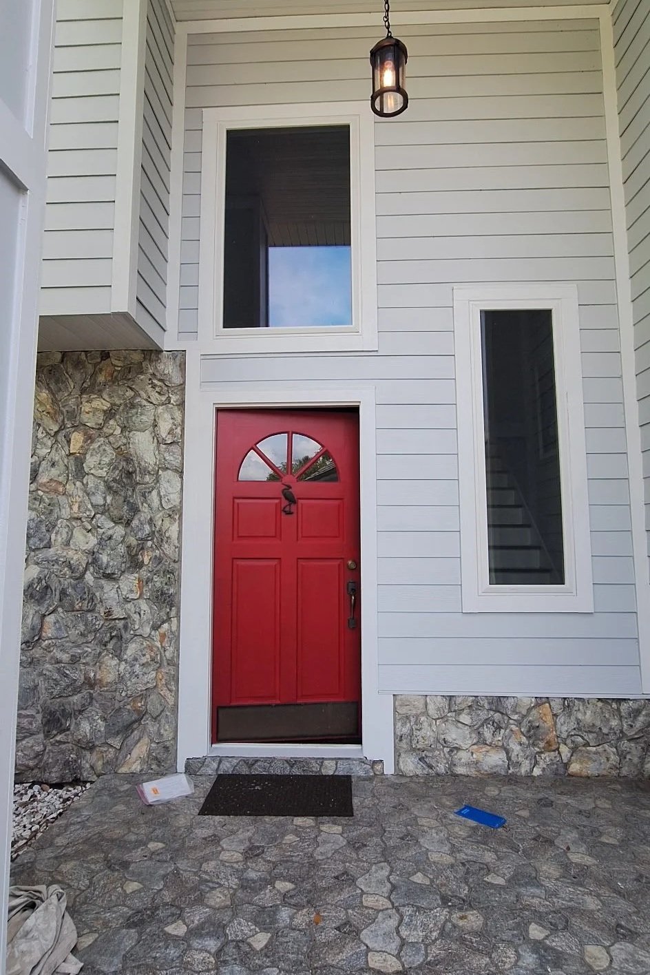 Modern white exterior home in Melbourne Florida with bold burgundy front door and stone accents freshly painted.