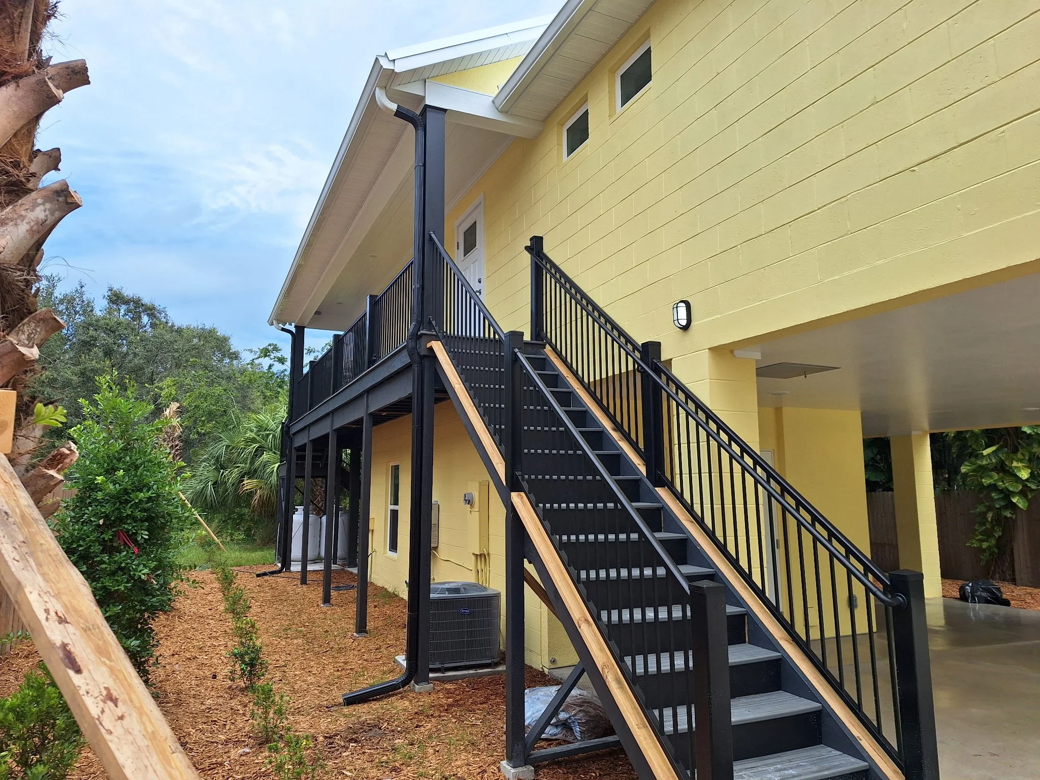 This staircase connects the elevated living space to the ground level, finished with durable black paint that adds contrast and complements the home’s coastal color palette.