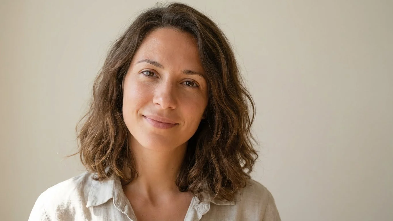 Femme portugaise, 32 ans, cheveux bruns ondulés, sourire doux, fond neutre lumineux, style simple et élégant.