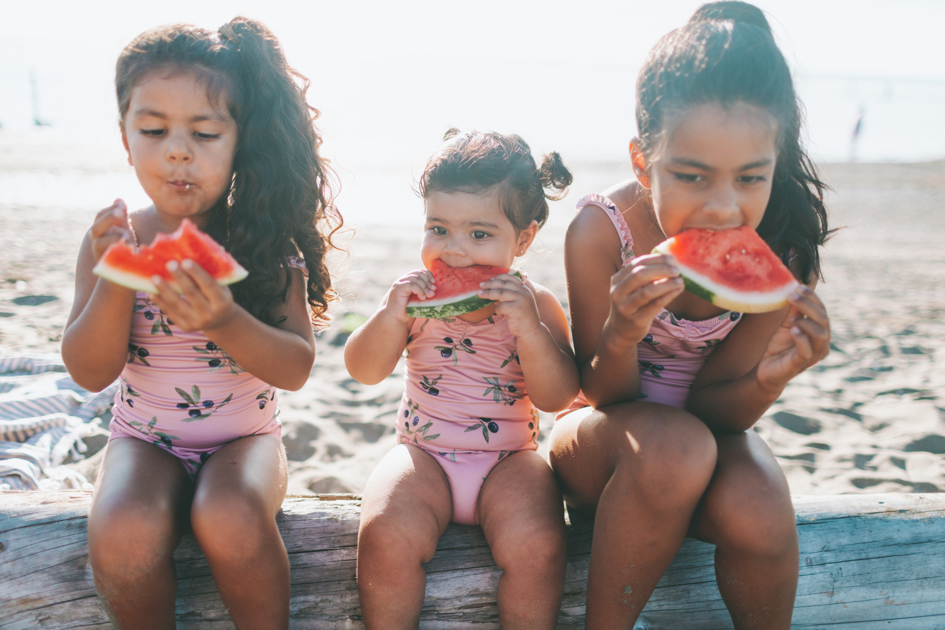 Kids enjoying slices of watermelon by the seaside