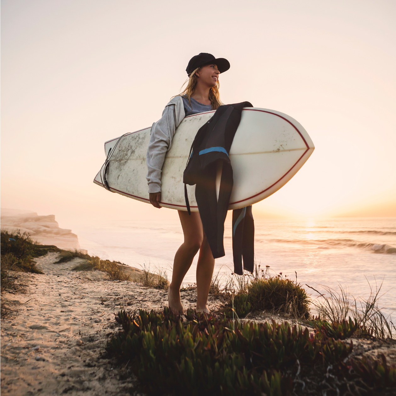 Surfer standing on the sand with their board, symbolising freedom and protection through health insurance