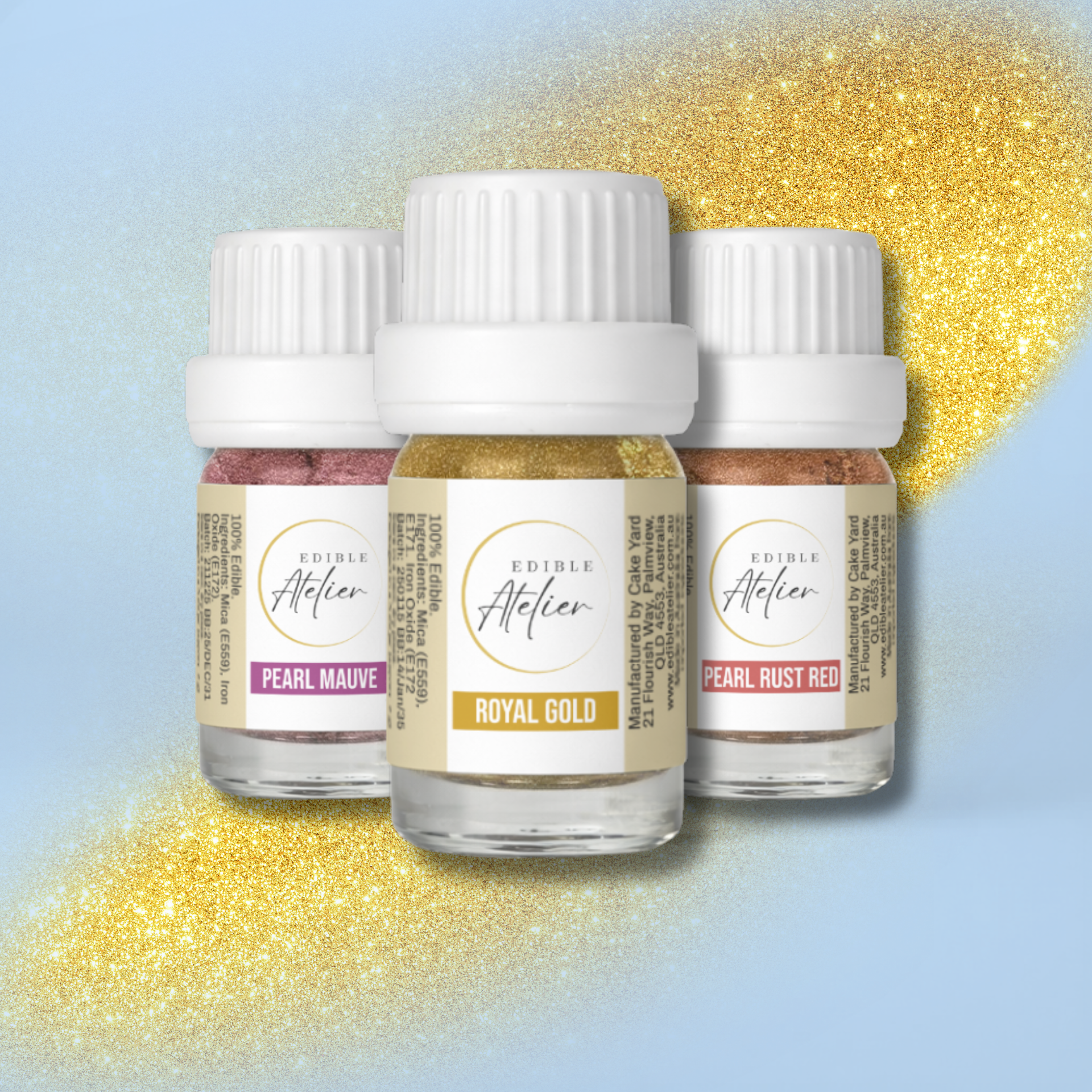 Three small bottles of edible glitter with white caps, labeled Pearl Mauve, Royal Gold, and Pearl Rust Red, arranged against a blue background with gold glitter accents.