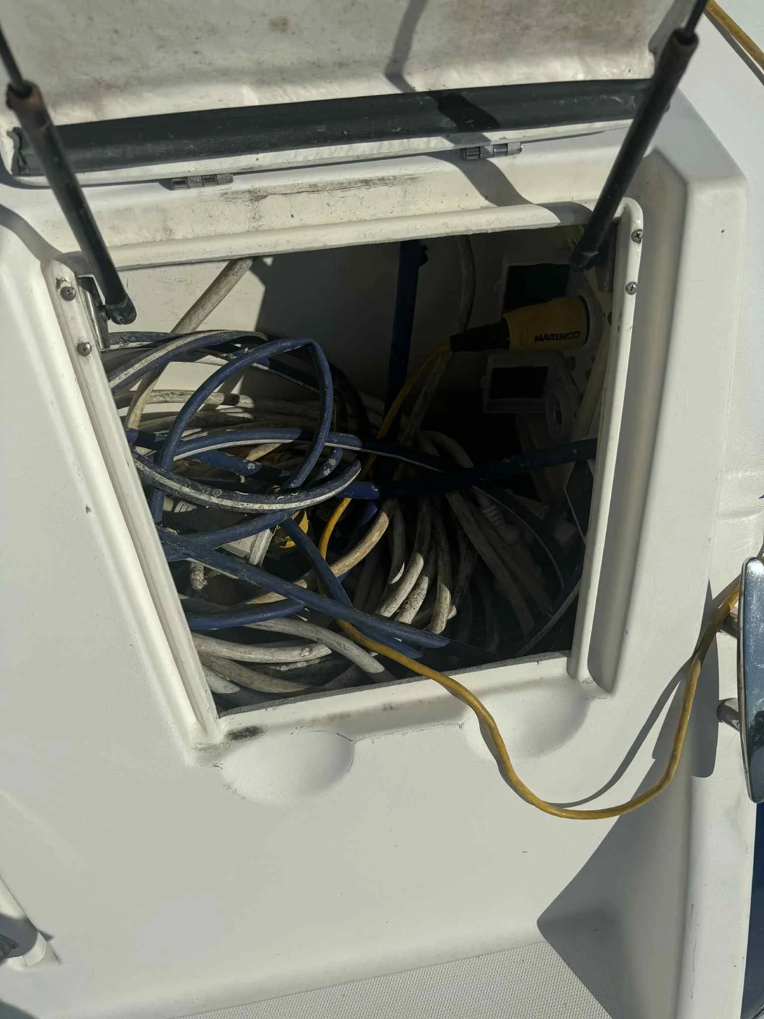 Open electrical panel with tangled black, gray, and yellow wires inside a white enclosure and a yellow wire hanging outside.