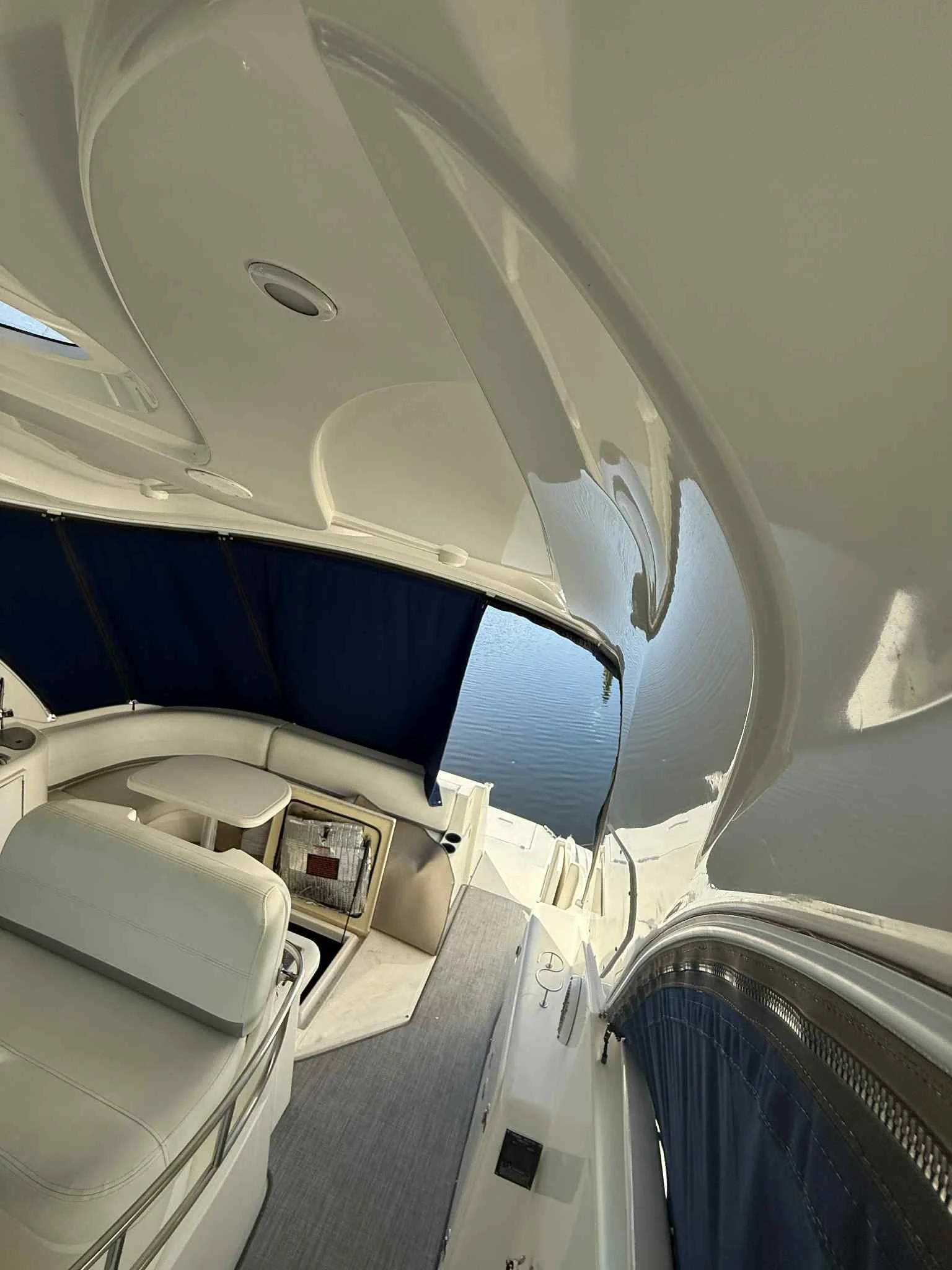 Interior of a yacht with seating, a small table, and windows overlooking water