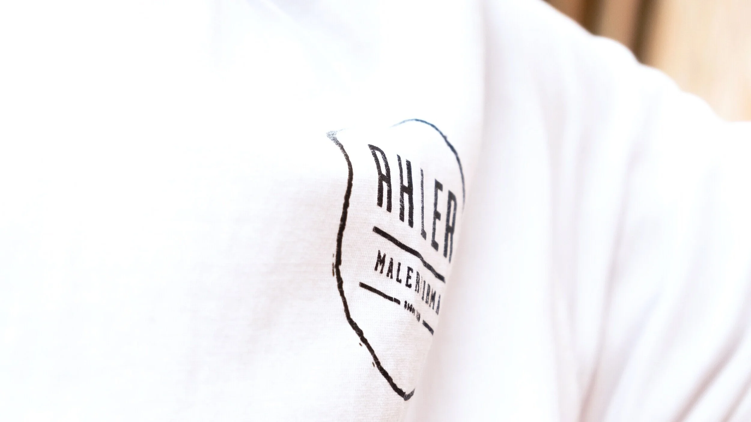 En hvid t-shirt med en sort print, der siger 'Theater' og 'Maleri'.