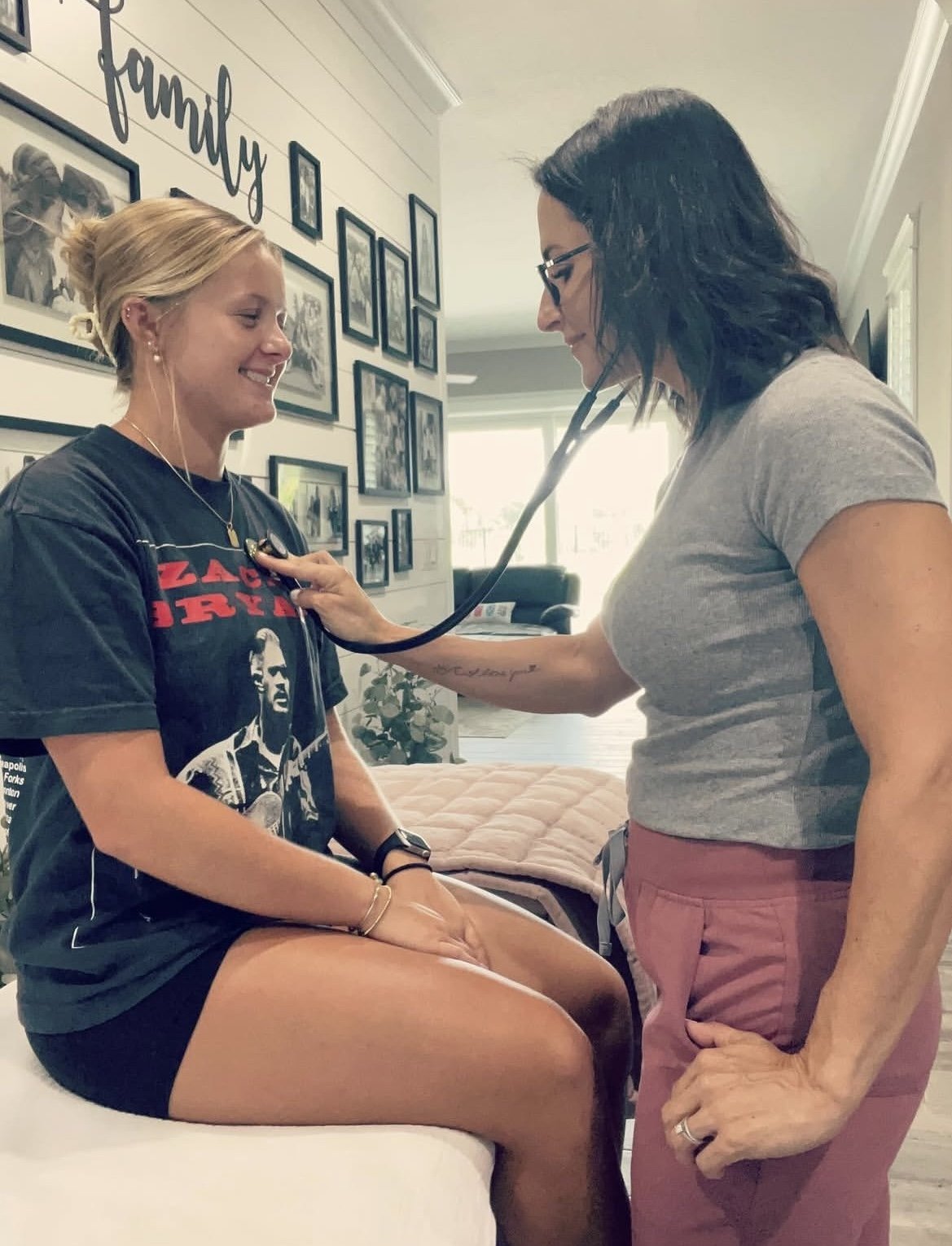 Nurse practitioner checking a teenager's heart rate in a friendly home setting.