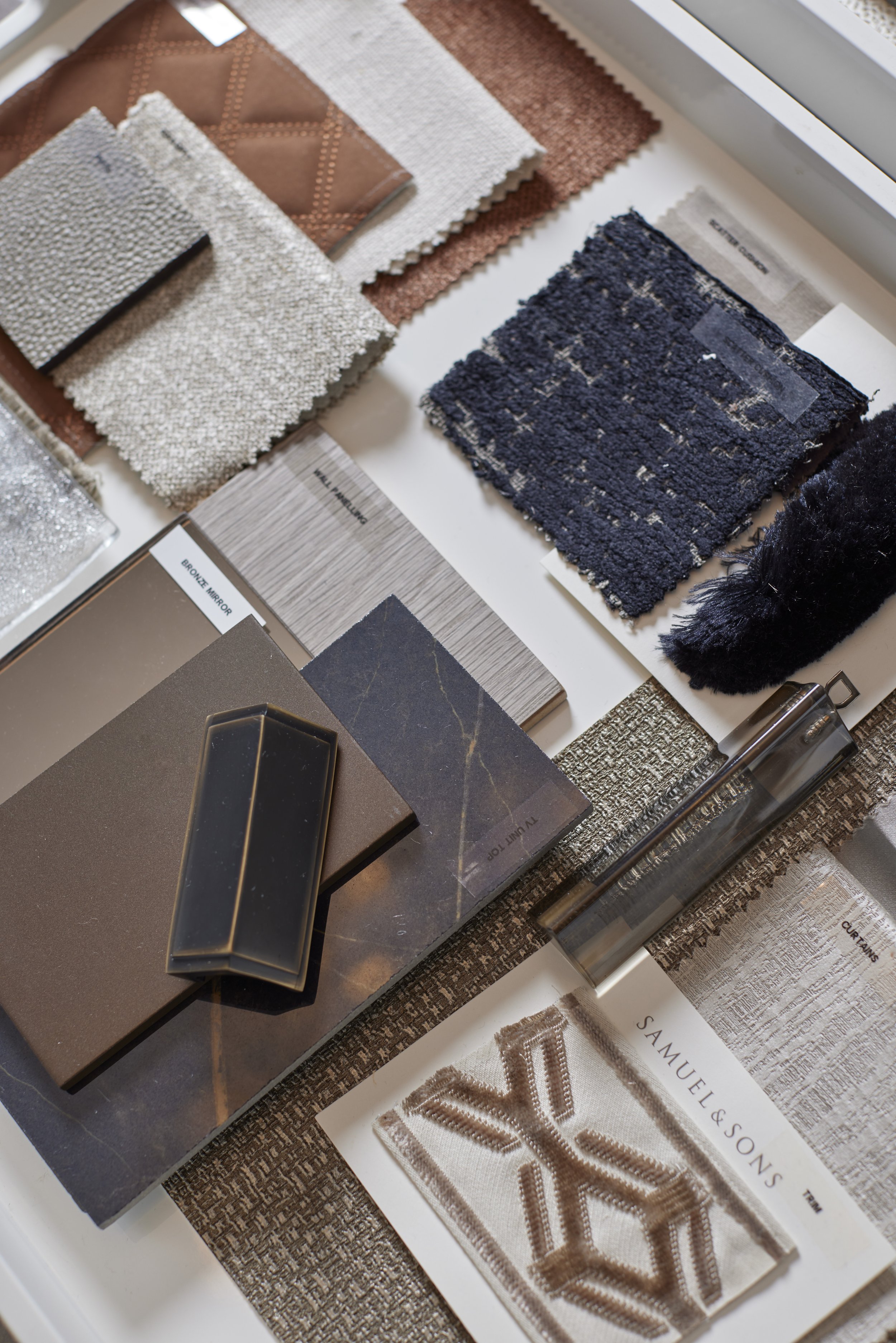 A collection of fabric swatches, material samples, and design books for interior decorating, featuring textiles, tiles, and color samples.