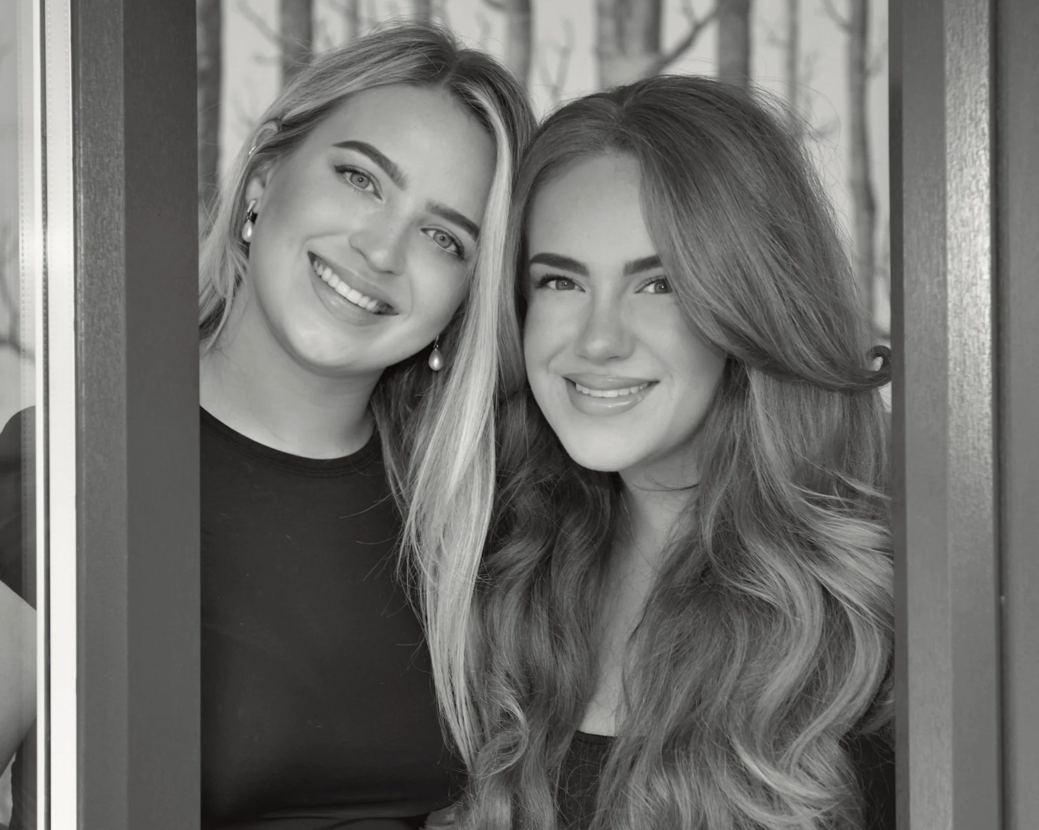 Two women smiling and looking at the camera, standing close together.