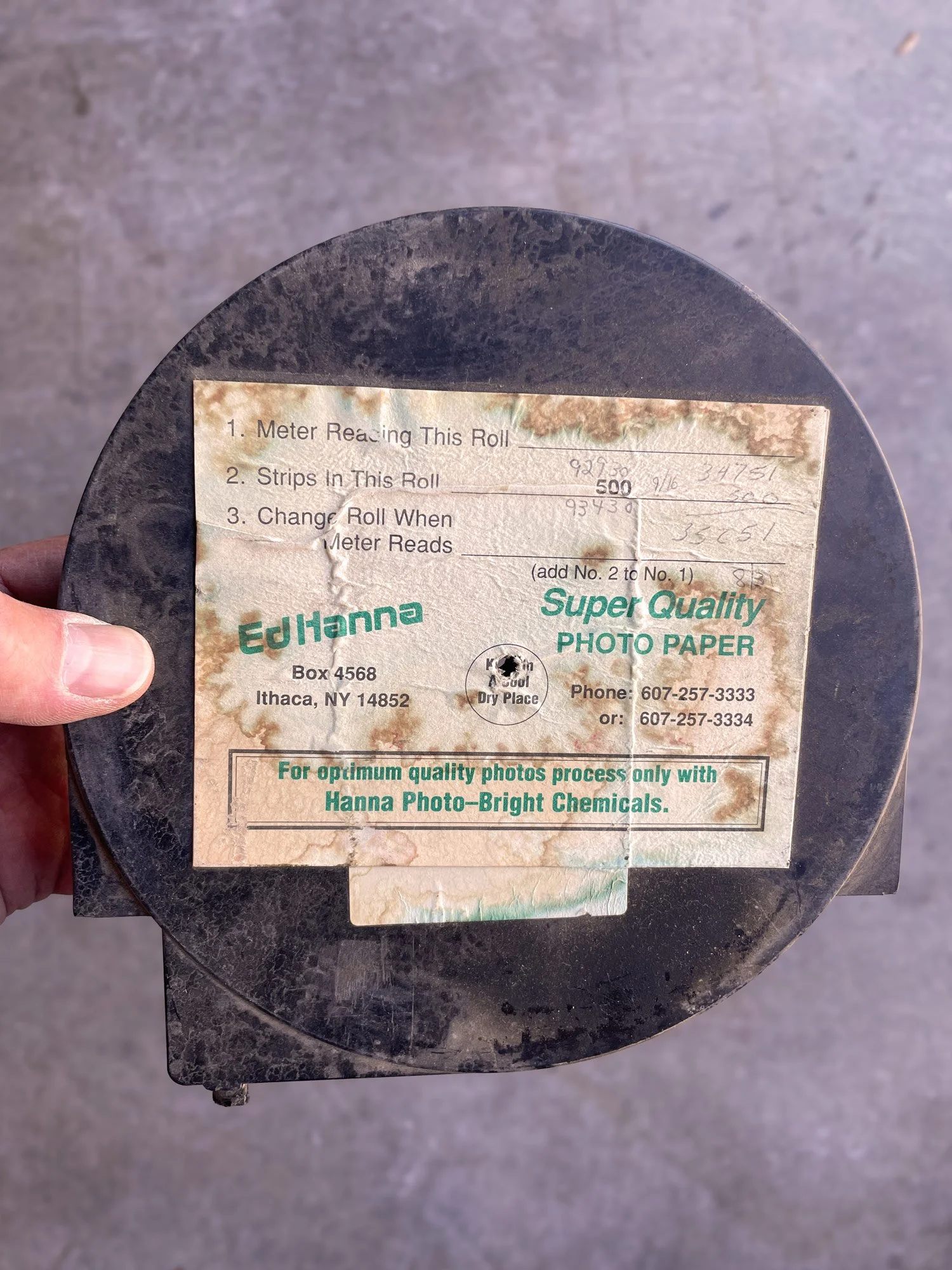 Vintage model 9 paper cassette, pictured close-up with a worn label, held in a person's hand, with a concrete floor background.