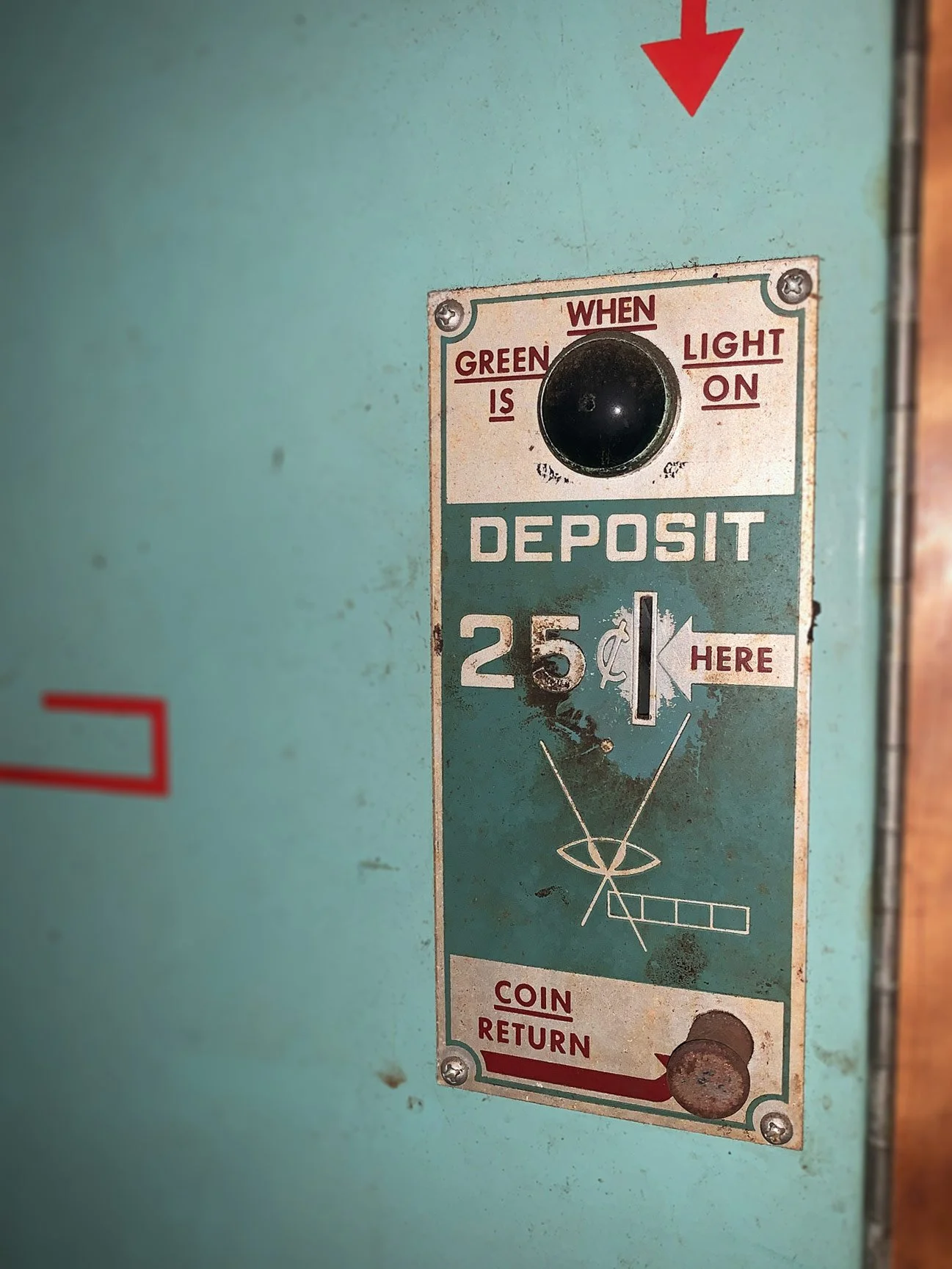 Auto-Photo Model 11 vintage photobooth, showing a close up of a vintage coin deposit slot with instructions to deposit 25 cents when the green light is on, and a coin return slot at the bottom.