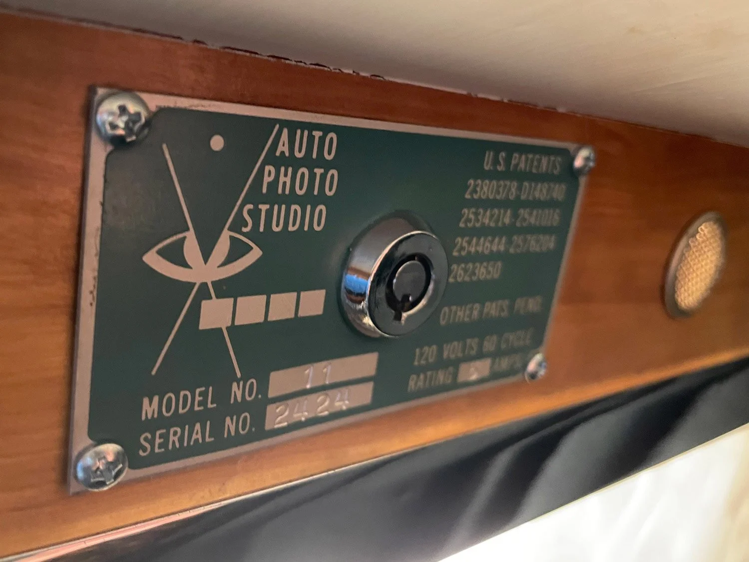 Auto-Photo Model 11 vintage photobooth serial plate above the upper flash window. Auto Photo Studio with patent information, model 11, serial number 2524, and other technical details.