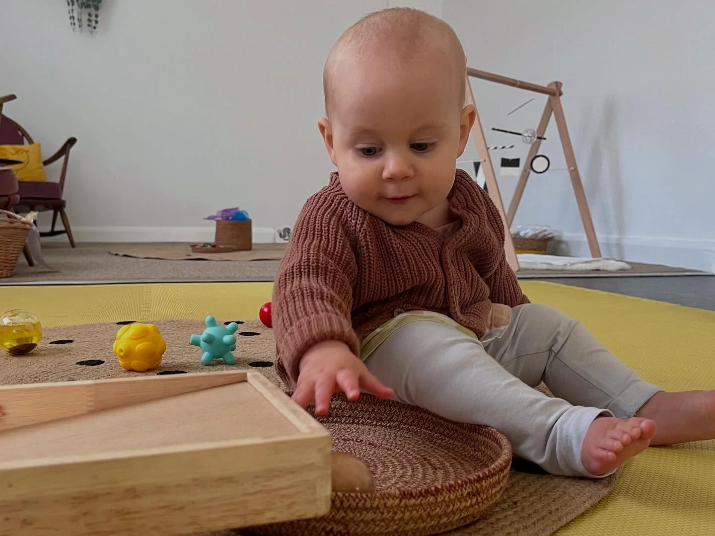 Baby reaching for a ball in an indoor play setting