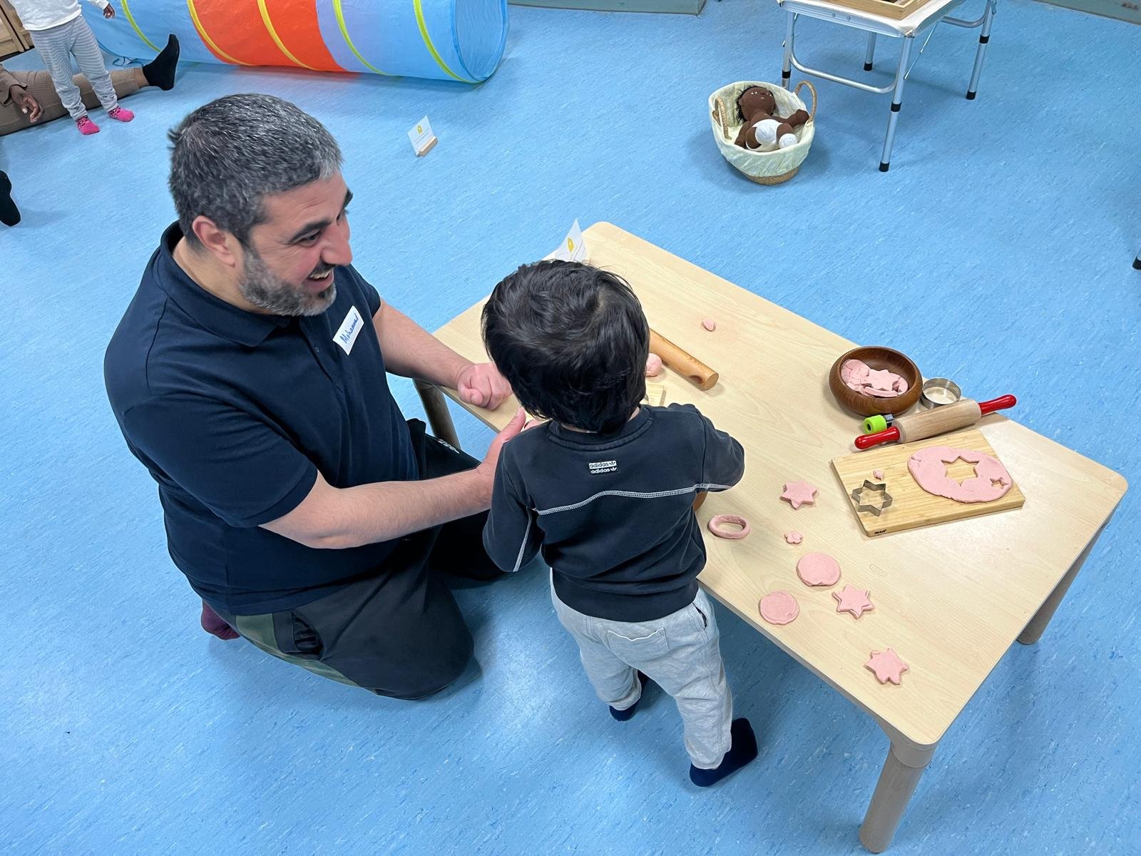 A father laughs with his son at an activity table