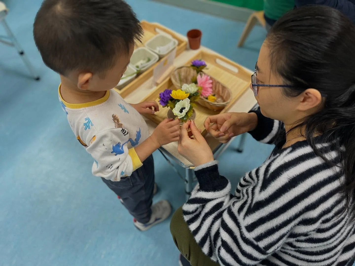 mother and toddler play with flowers