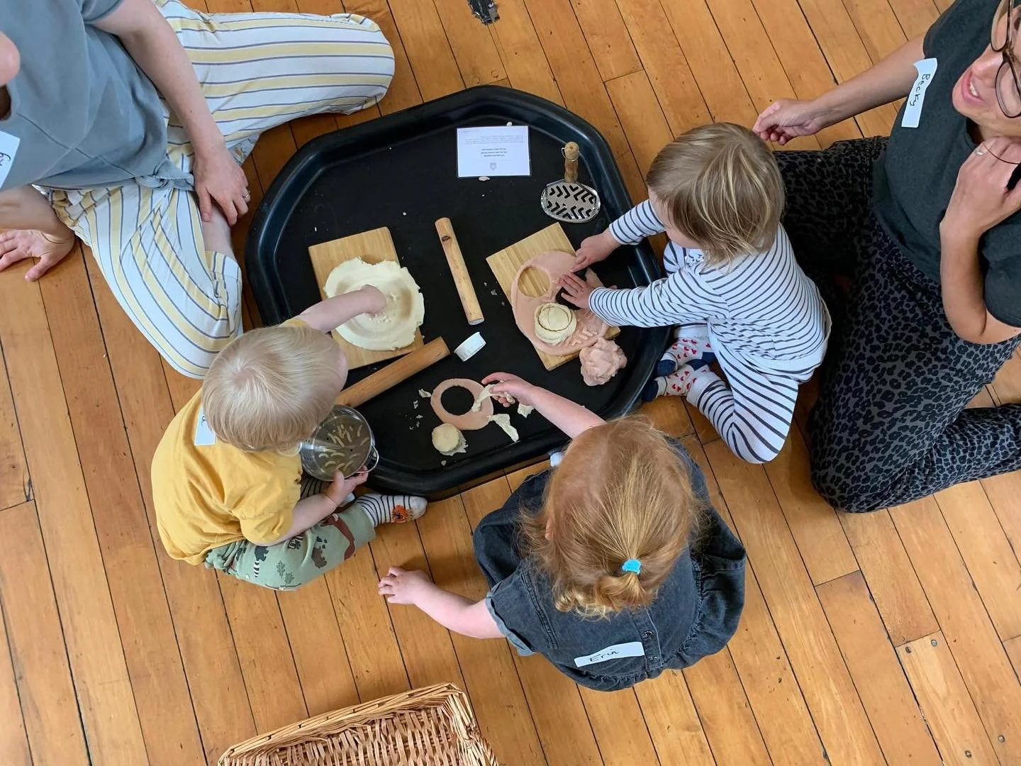 3 toddlers sat at a messy tray playing with playdough