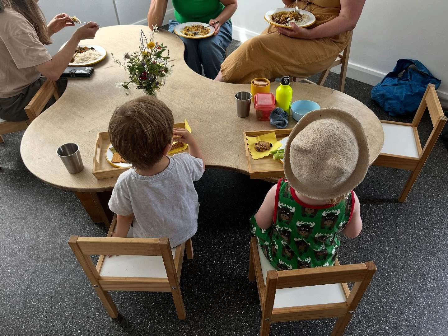 2 toddlers sat eating lunch with 3 adults