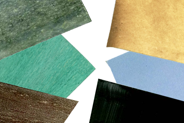 Various textured paper pieces in different colors including green, brown, black, blue, and gold, arranged unevenly on a white background.