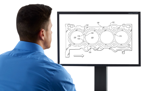 Person looking at a computer monitor displaying a technical diagram of an engine part.