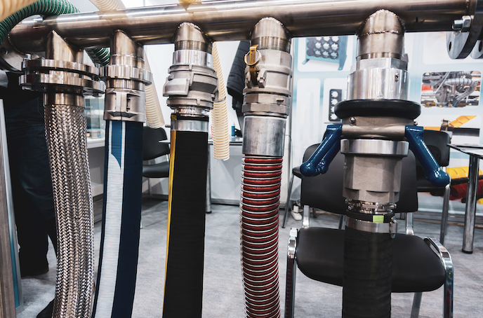 Multiple industrial pipes and hoses with various connectors and insulation, displayed in a laboratory or manufacturing setting.