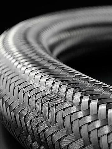Close-up of a metallic, woven, flexible tube or hose with a textured pattern.
