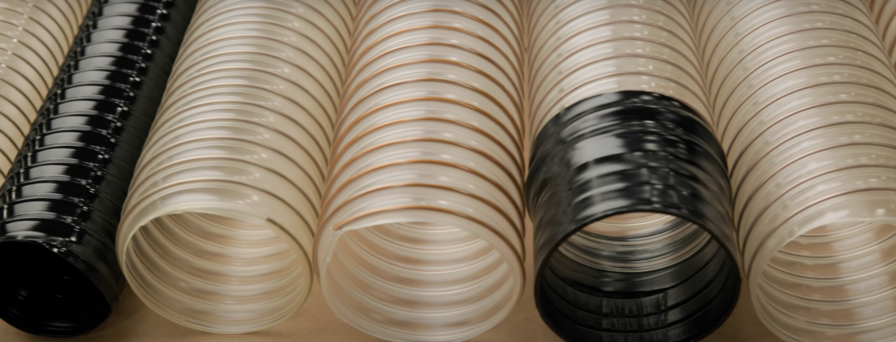 Various plastic hoses in black, white, and clear colors arranged in parallel.