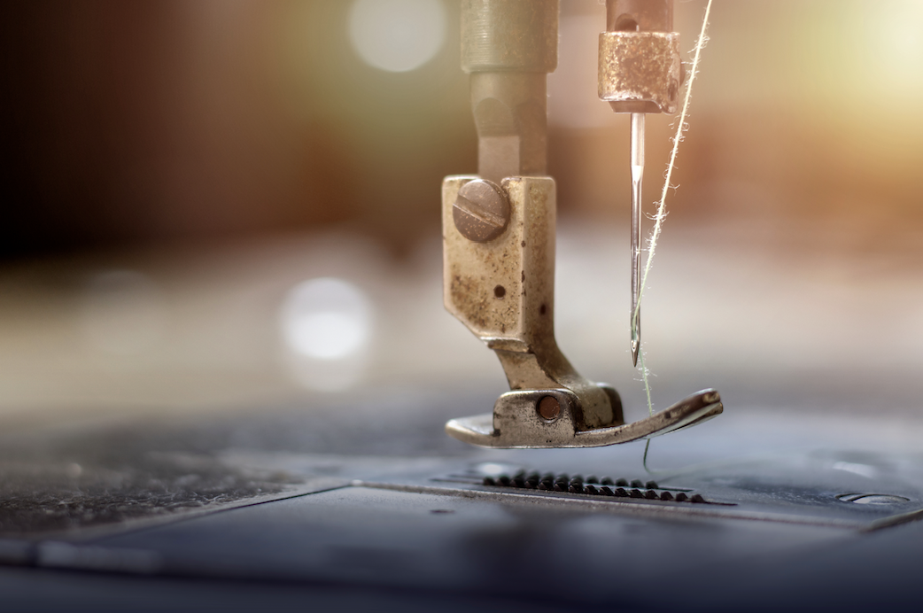 Close-up of a sewing machine needle and presser foot on fabric.
