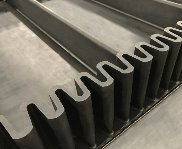 Close-up of black plastic or rubber parts with U-shaped notches, likely part of a machine or industrial equipment.