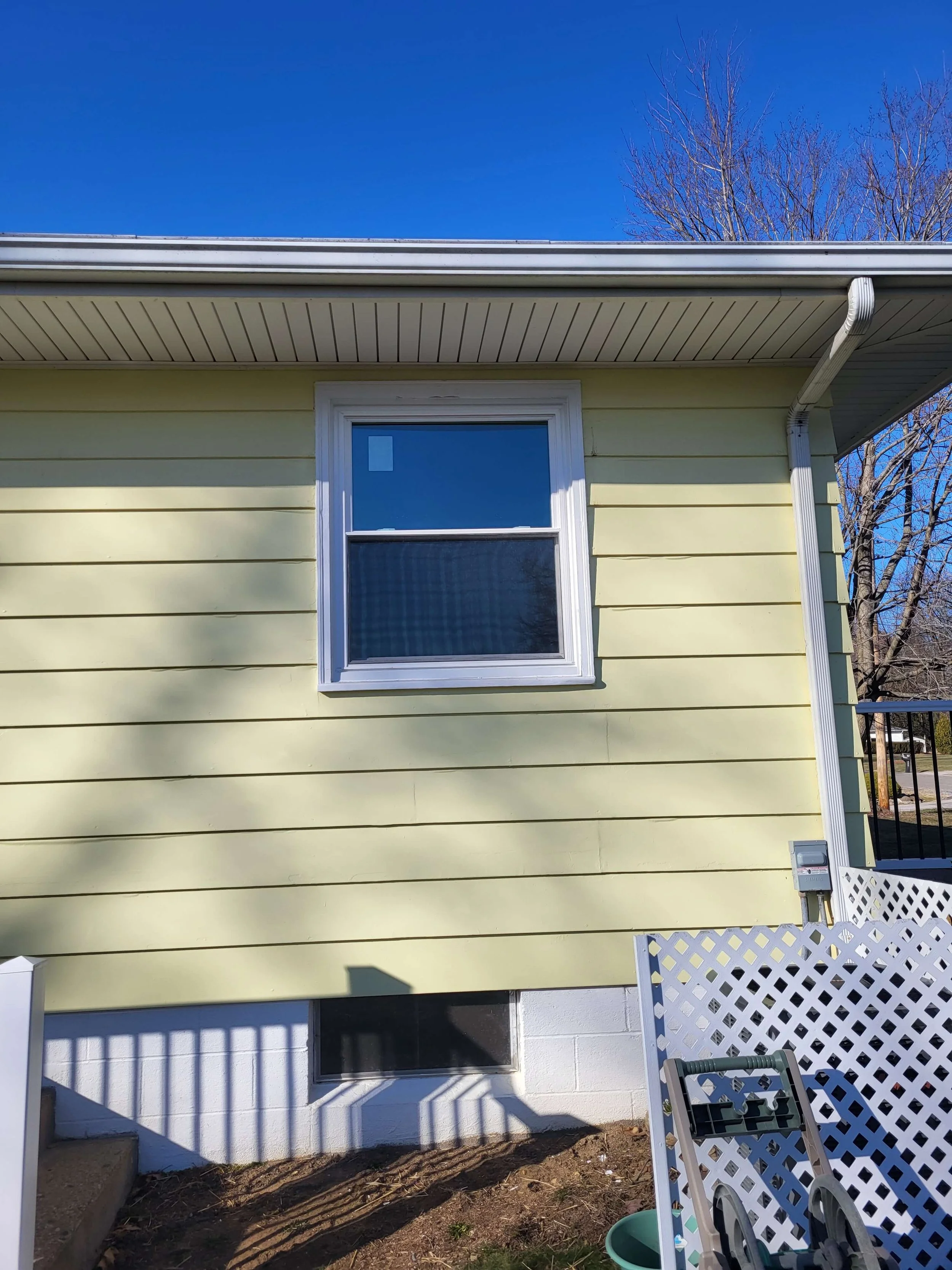 Close up view of newly installed white vinyl double hung windows on a light yellow siding home in Cuyahoga Falls Ohio