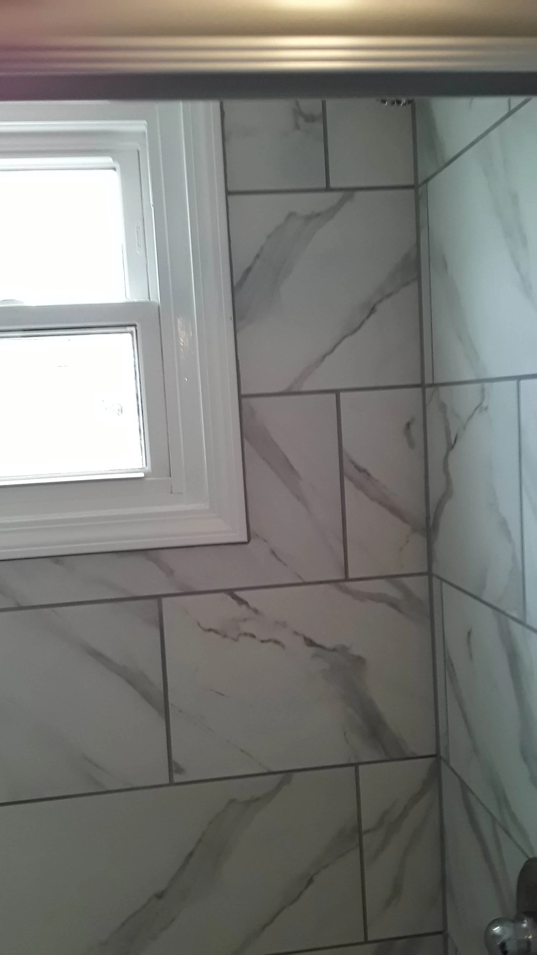 Moisture resistant bathroom replacement window with white vinyl framing set against custom marble tiled shower walls in Akron Ohio