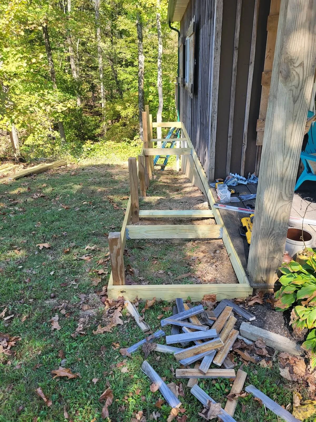 Close-up shot of the raw wood joist framing and rim board skeleton being leveled across the hillside cabin walkway.
