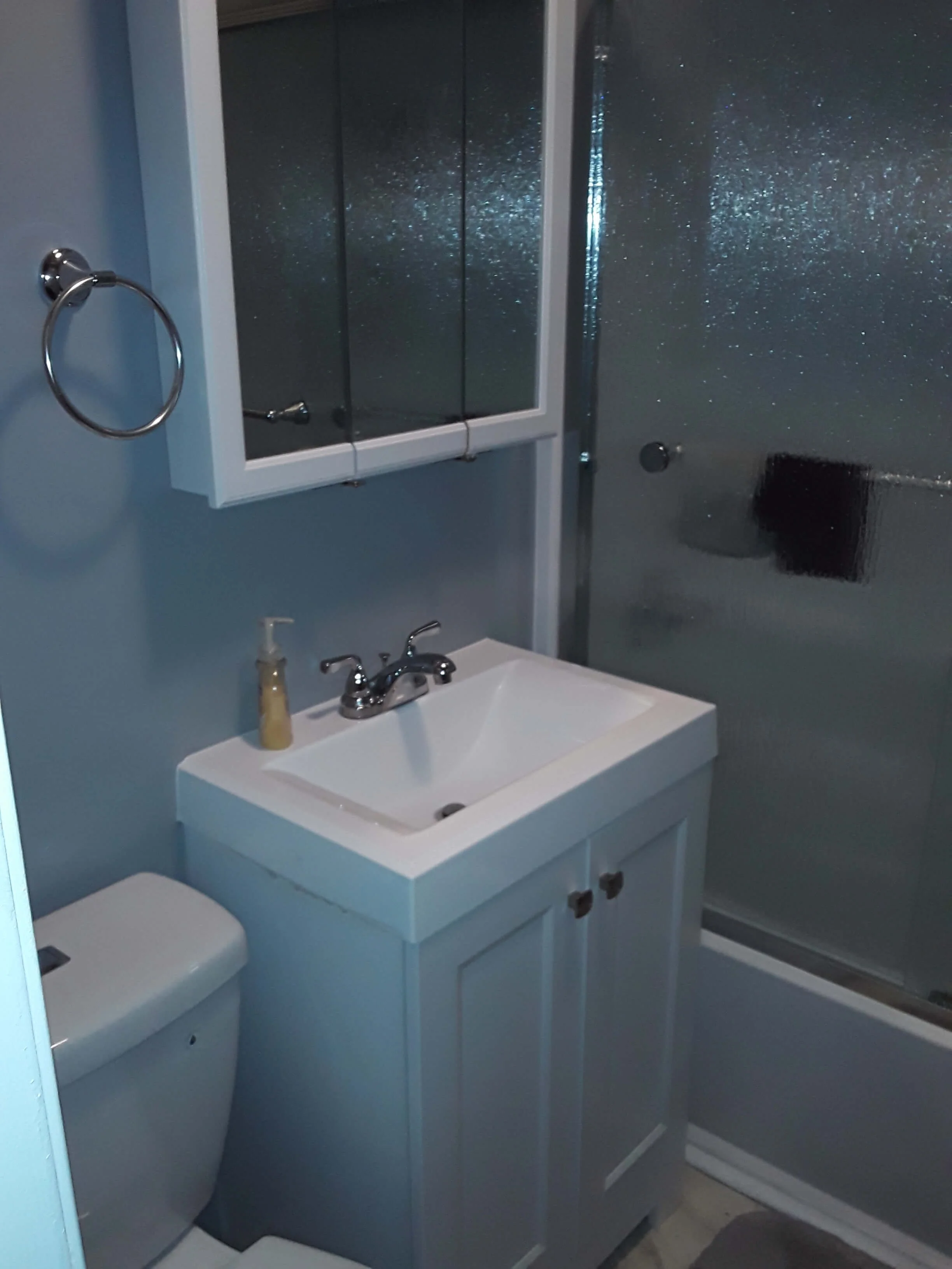 DLR Construction small compact bathroom remodel with white vanity medicine cabinet and glass sliding shower doors in Cleveland Ohio