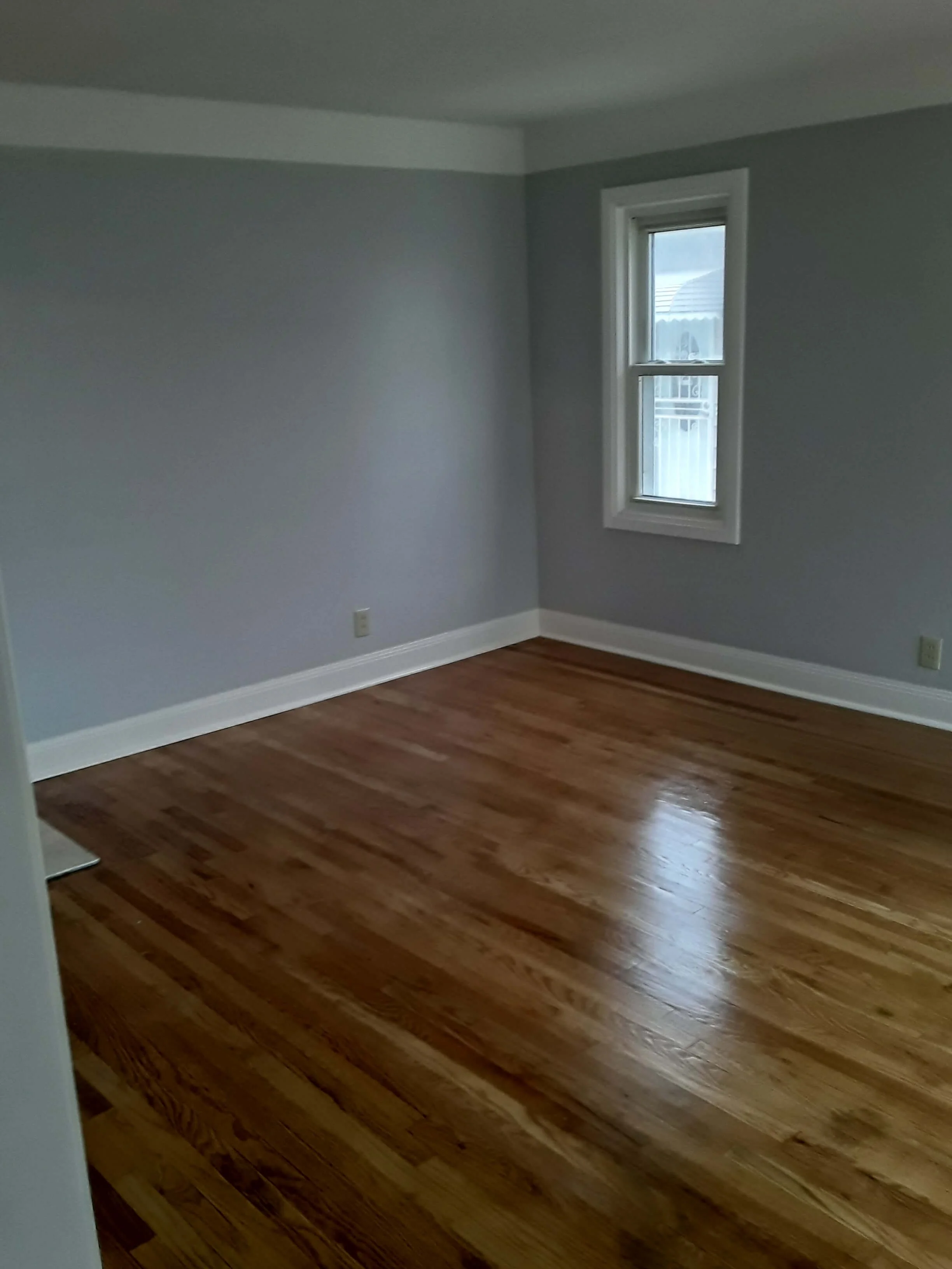 Newly sanded and refinished hardwood flooring with a satin polyurethane finish and freshly painted gray walls by DLR Construction in Cleveland, Ohio.