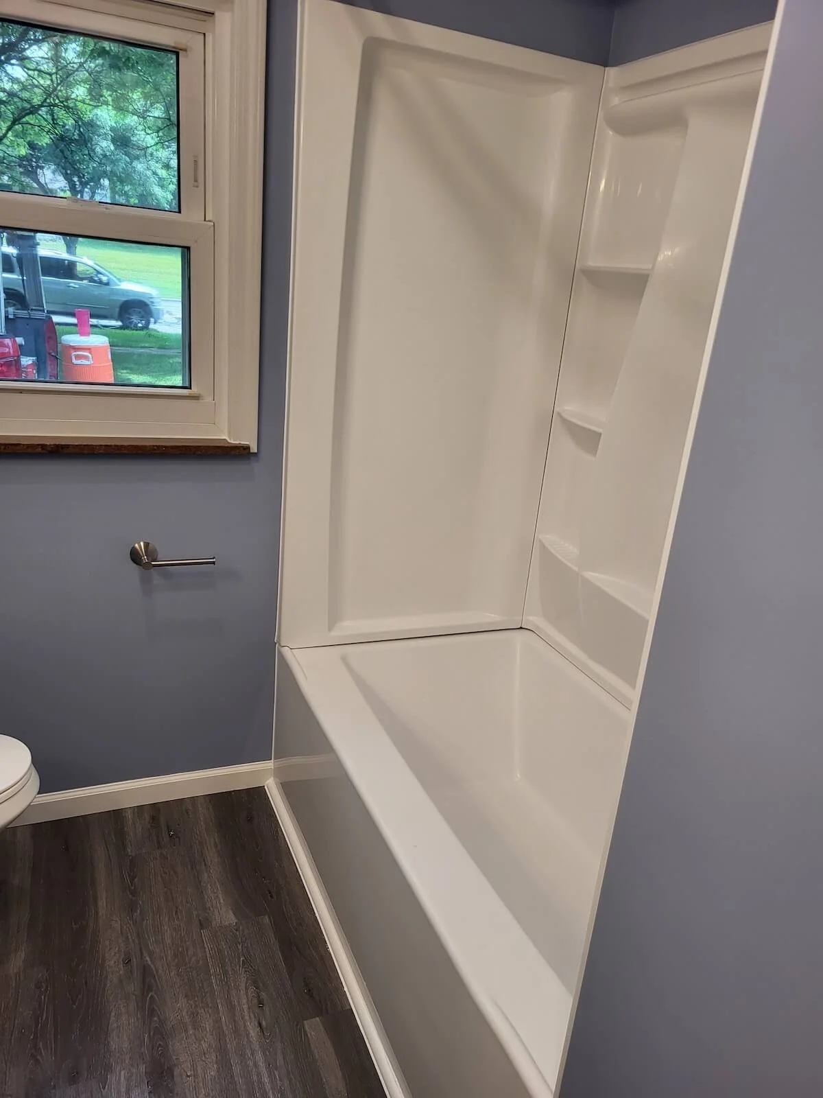 Dark gray luxury vinyl flooring running seamlessly from a renovated bathroom into a residential hallway.