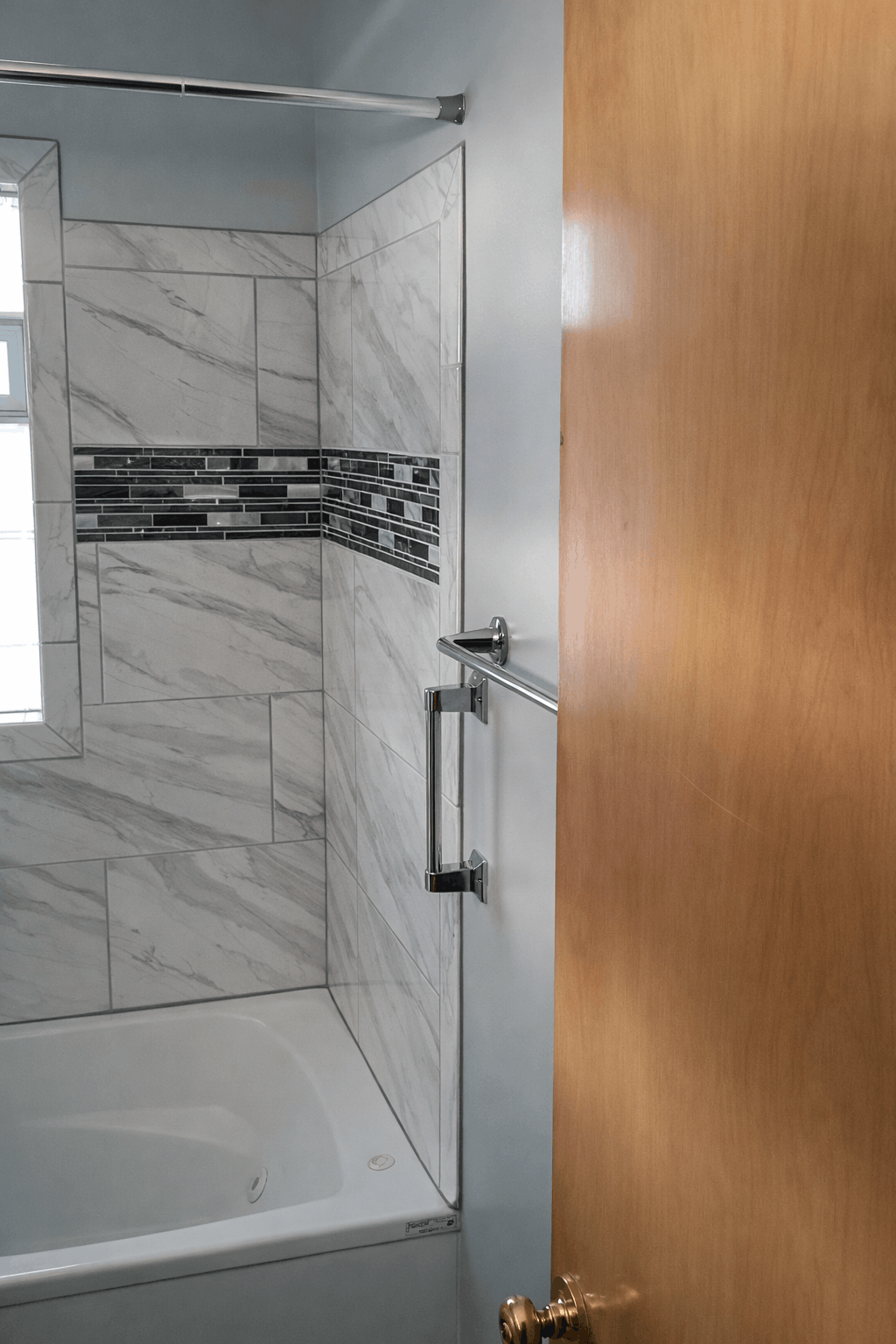 Close-up of chrome towel bar installed on freshly refinished smooth walls in a custom Cleveland, OH bathroom remodel featuring vessel sink and tiled shower