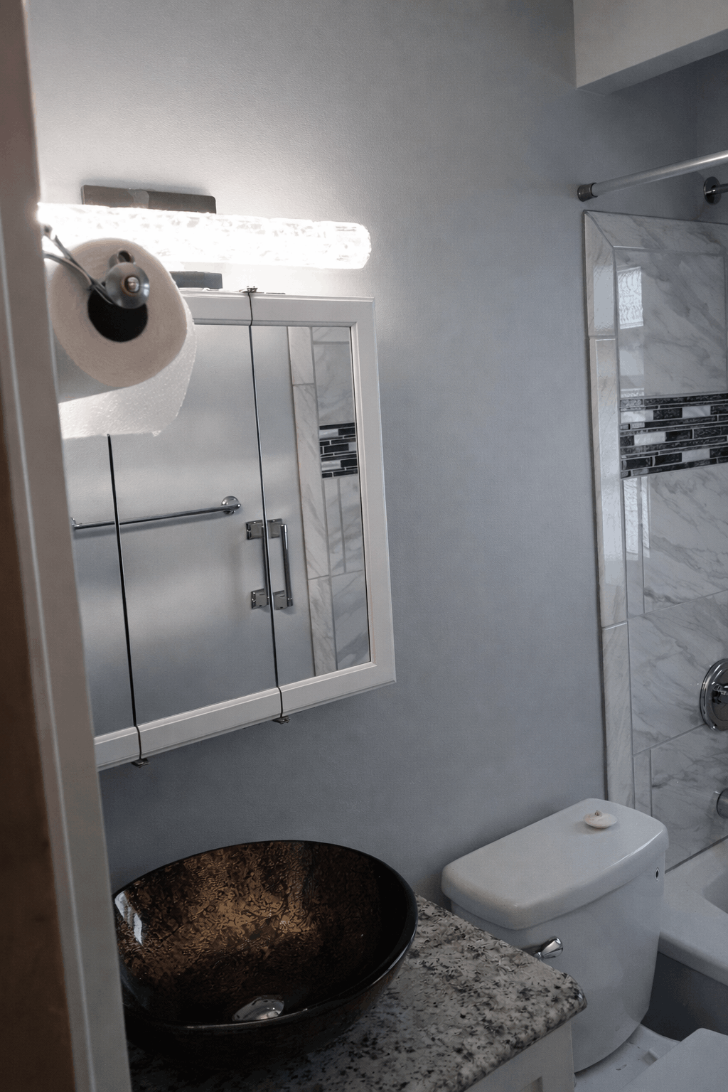 Wall-mounted medicine cabinet with integrated LED light bar above a vessel sink in a custom Cleveland bathroom remodel