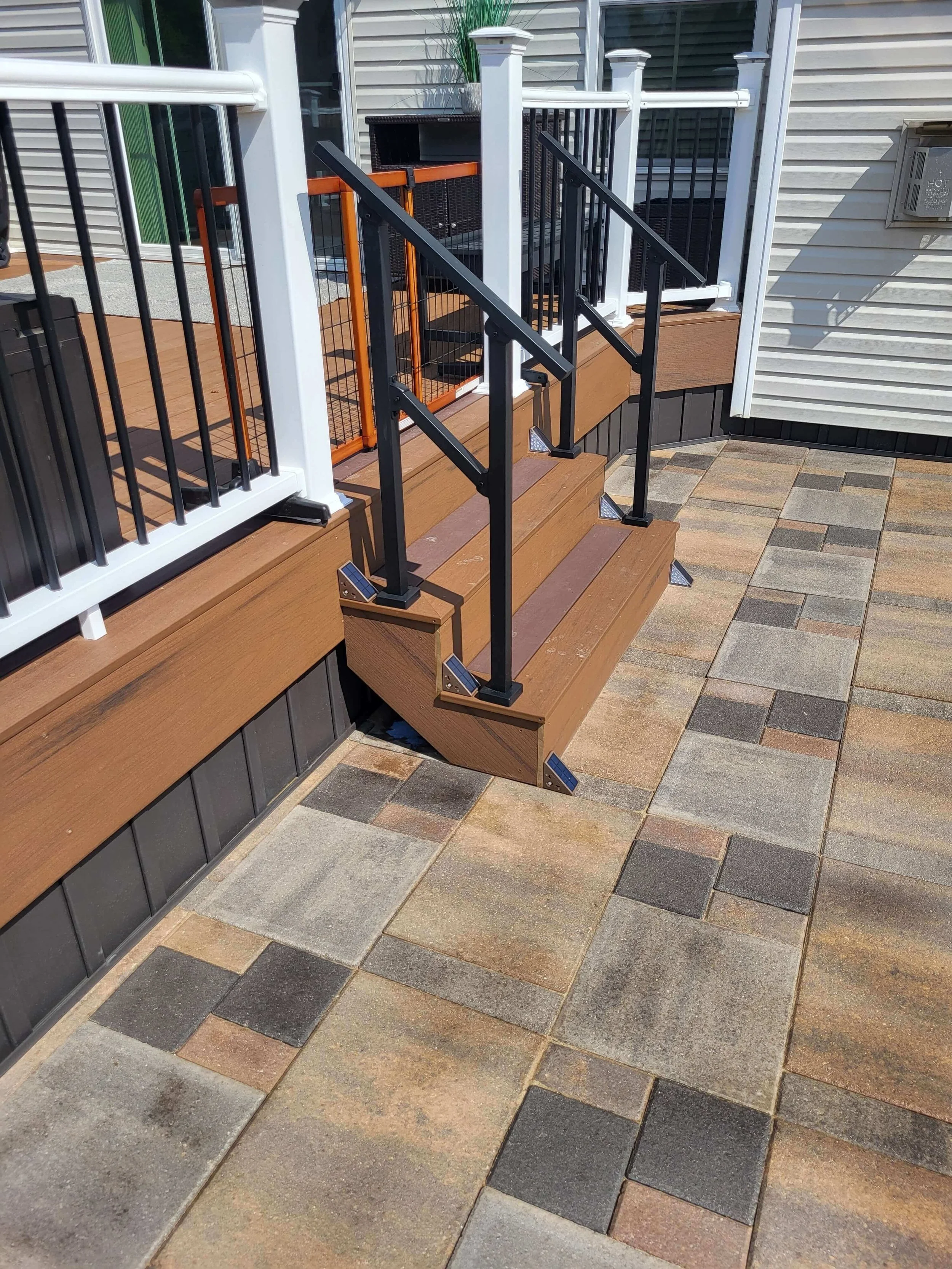 Custom composite deck with white vinyl handrails and paved patio installation by DLR Construction in Akron Ohio.