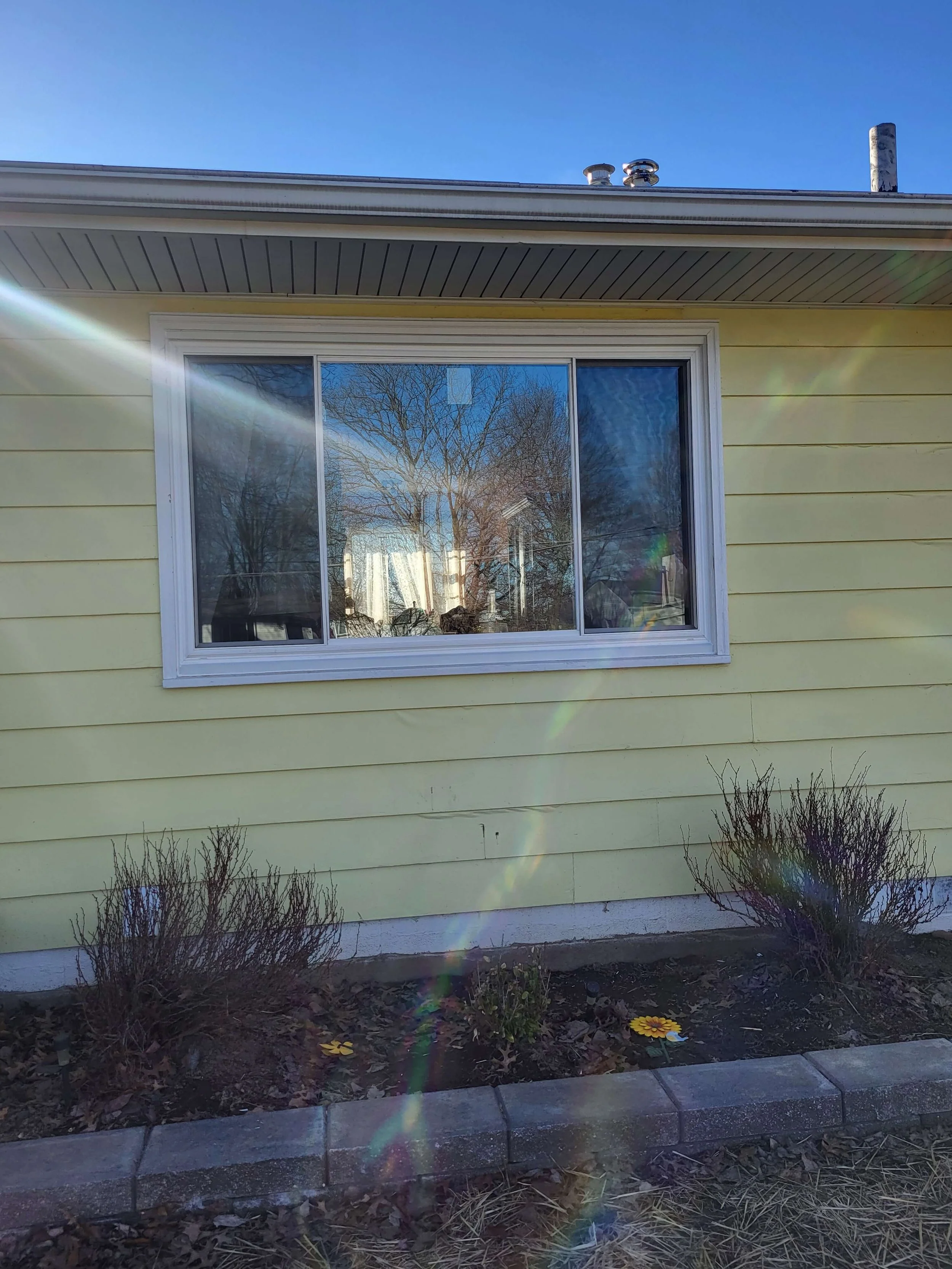 Energy efficient residential sliding window installation on a light green siding home in Cuyahoga Falls Ohio