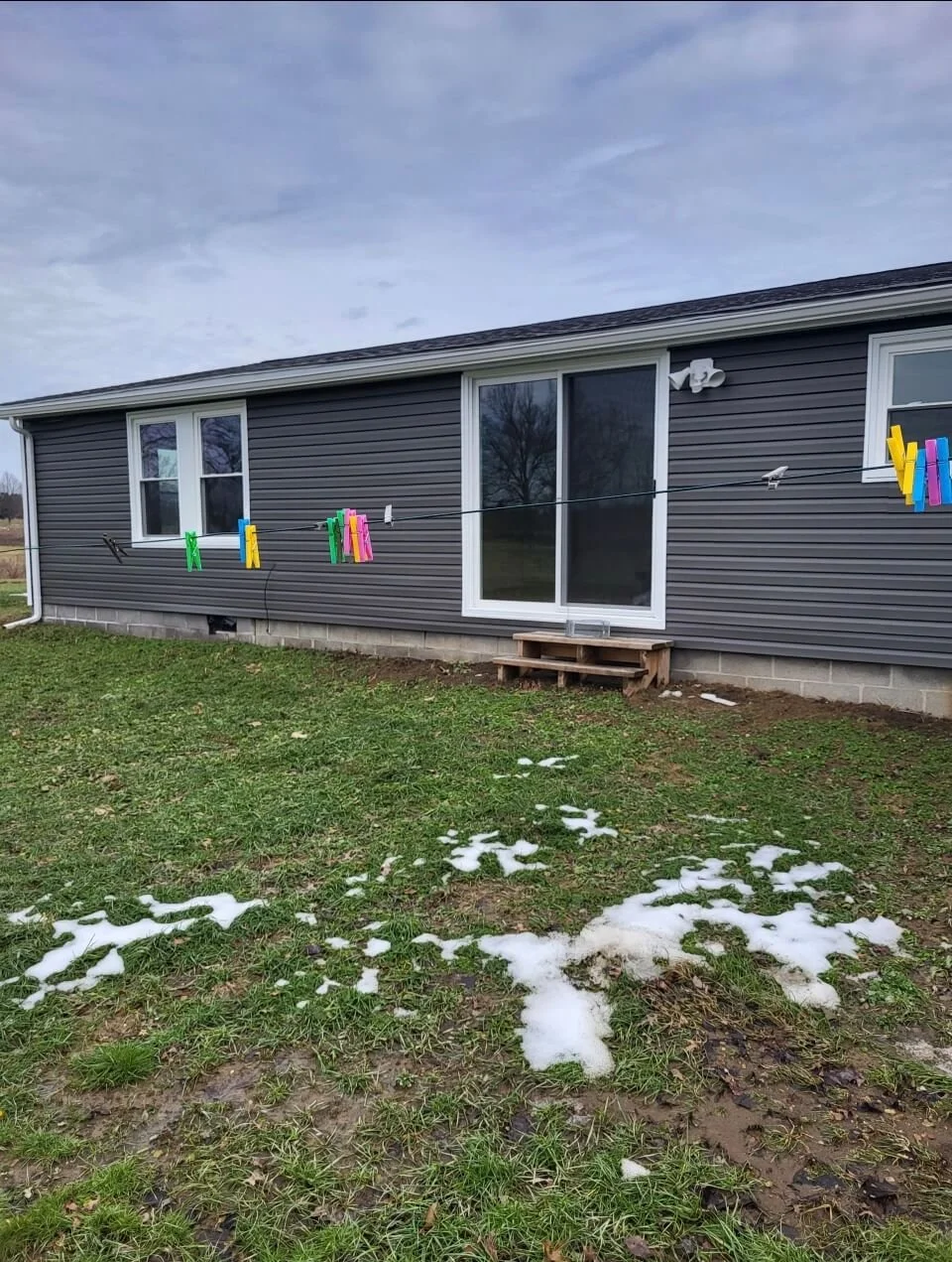 Rear exterior view of a residential home remodel featuring newly installed dark gray vinyl siding and white window frames by DLR Construction.