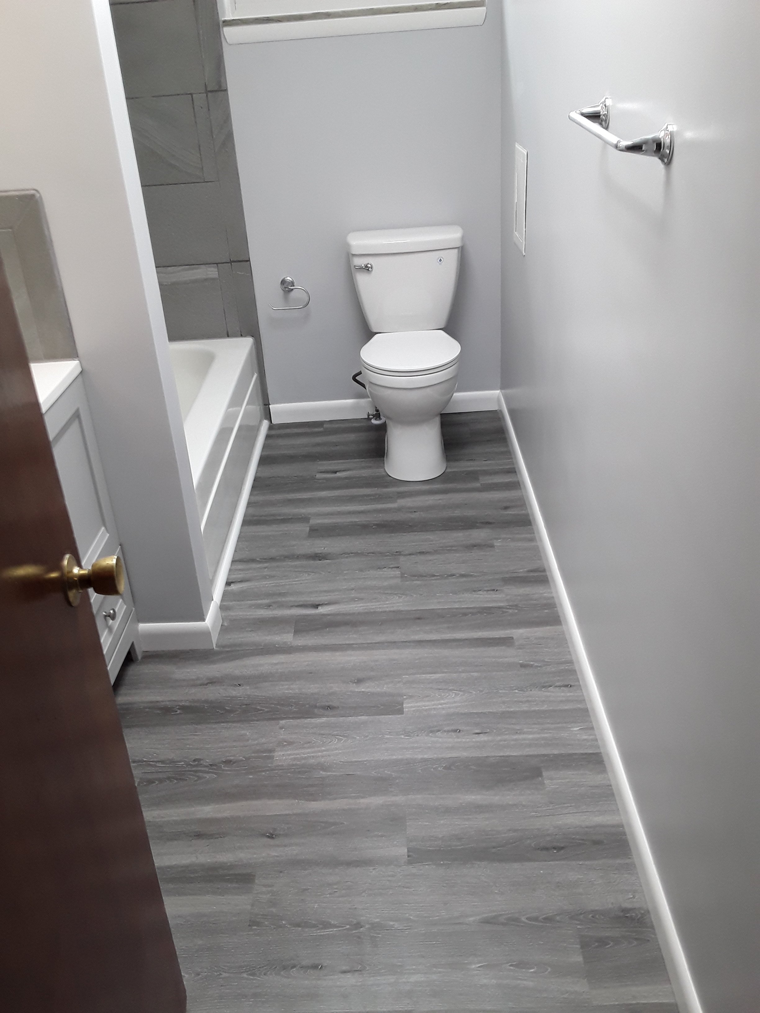 Durable luxury vinyl plank flooring installed throughout bathroom, showing moisture-resistant finish and clean layout.