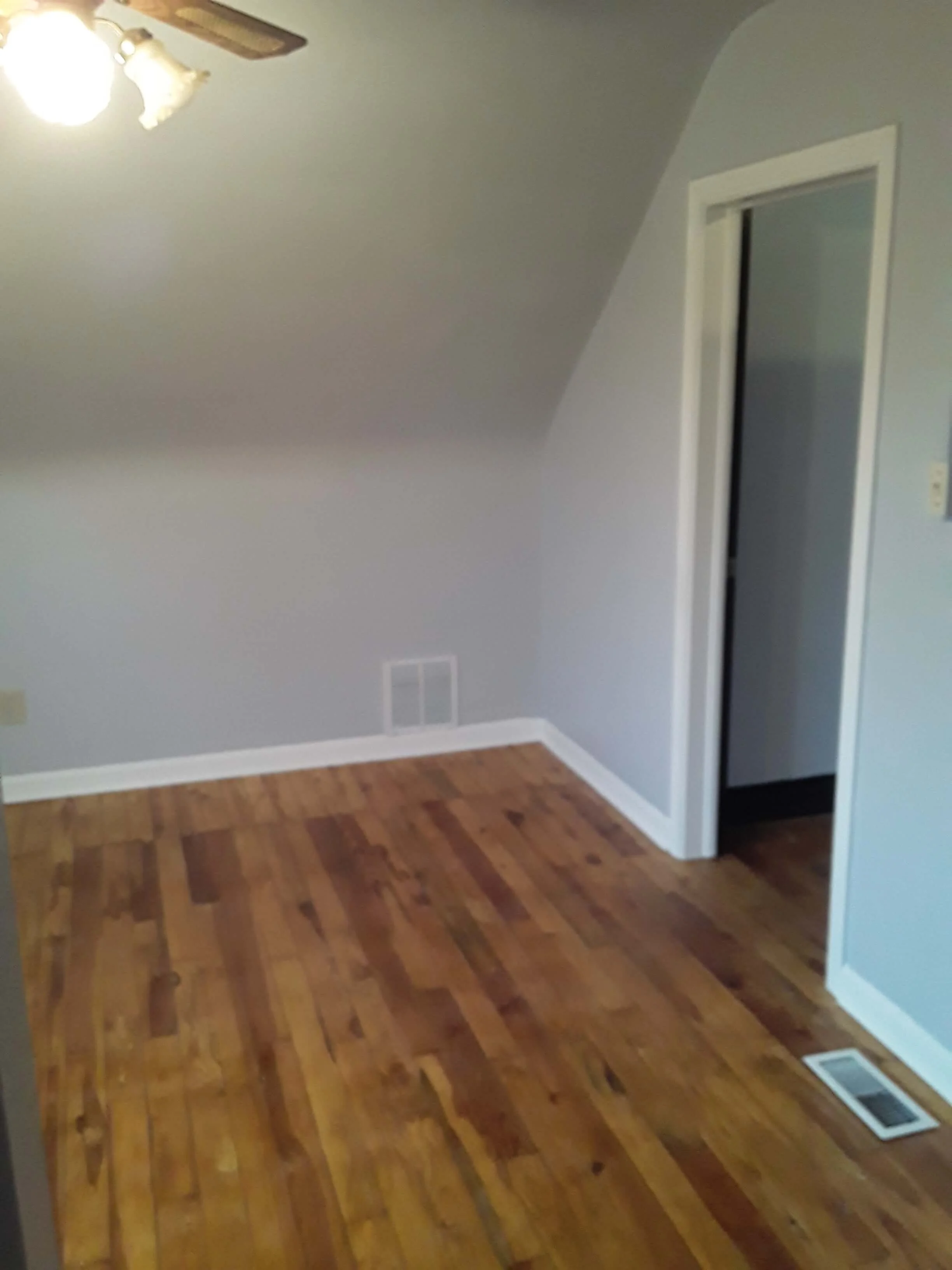 Full room restoration with sanded hardwood flooring, fresh paint, and ceiling refinishing