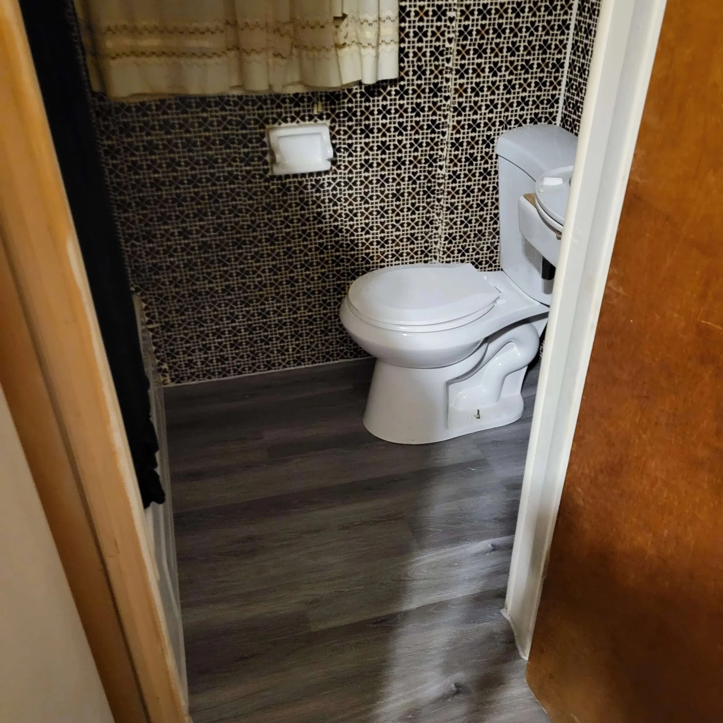 Finished bathroom renovation with new flooring, trim, and toilet after repairing water damage from a leaking toilet.