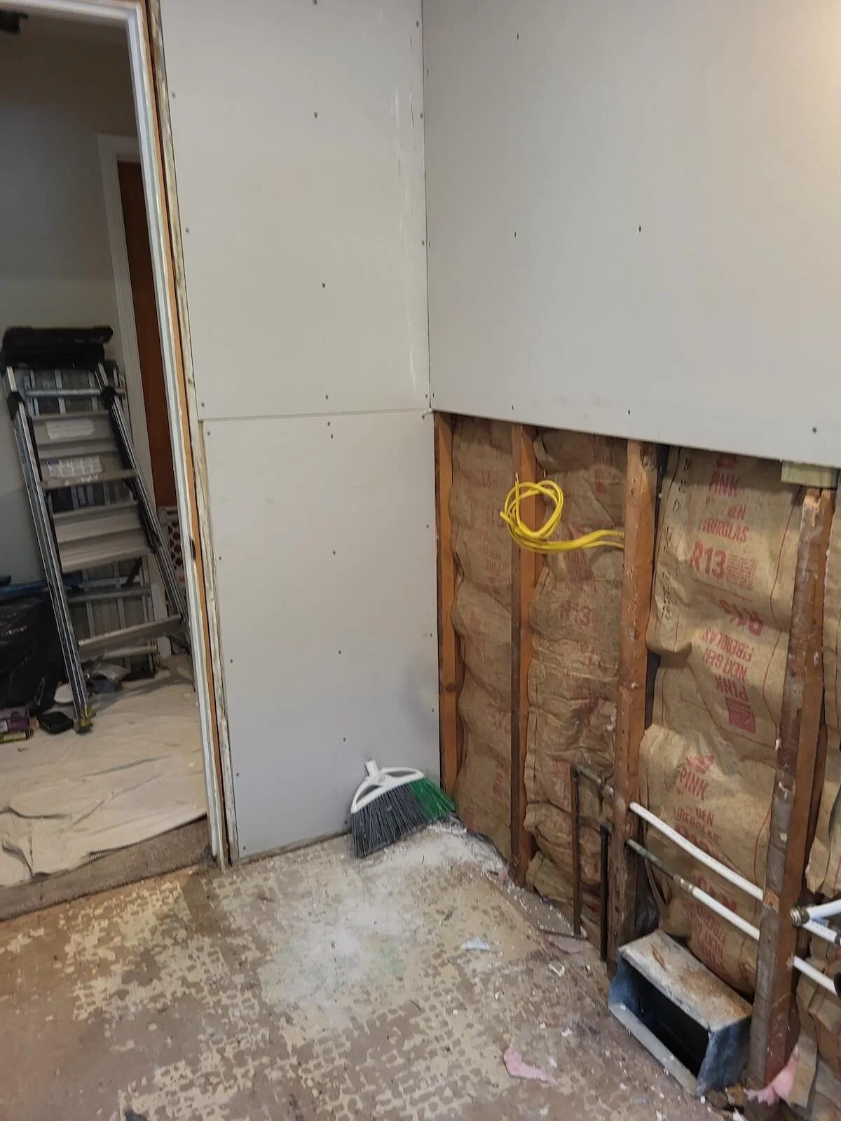 Down to the studs home bathroom framing showcasing exposed yellow electrical lines and wall framing structures.
