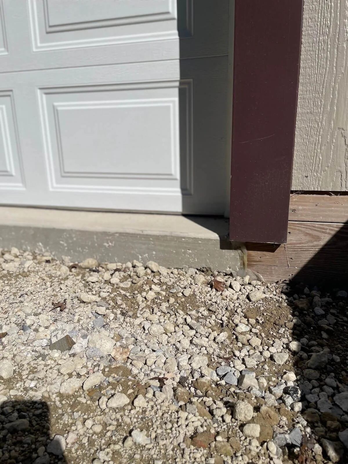 Close up detail showing the heavy duty concrete foundation edge and pressure treated perimeter base blocking insulation alignment.