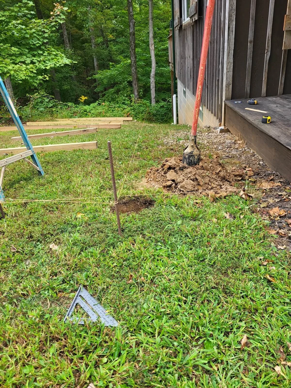 A steep grass slope running alongside a rustic log cabin home before a custom bridge connector deck was built.