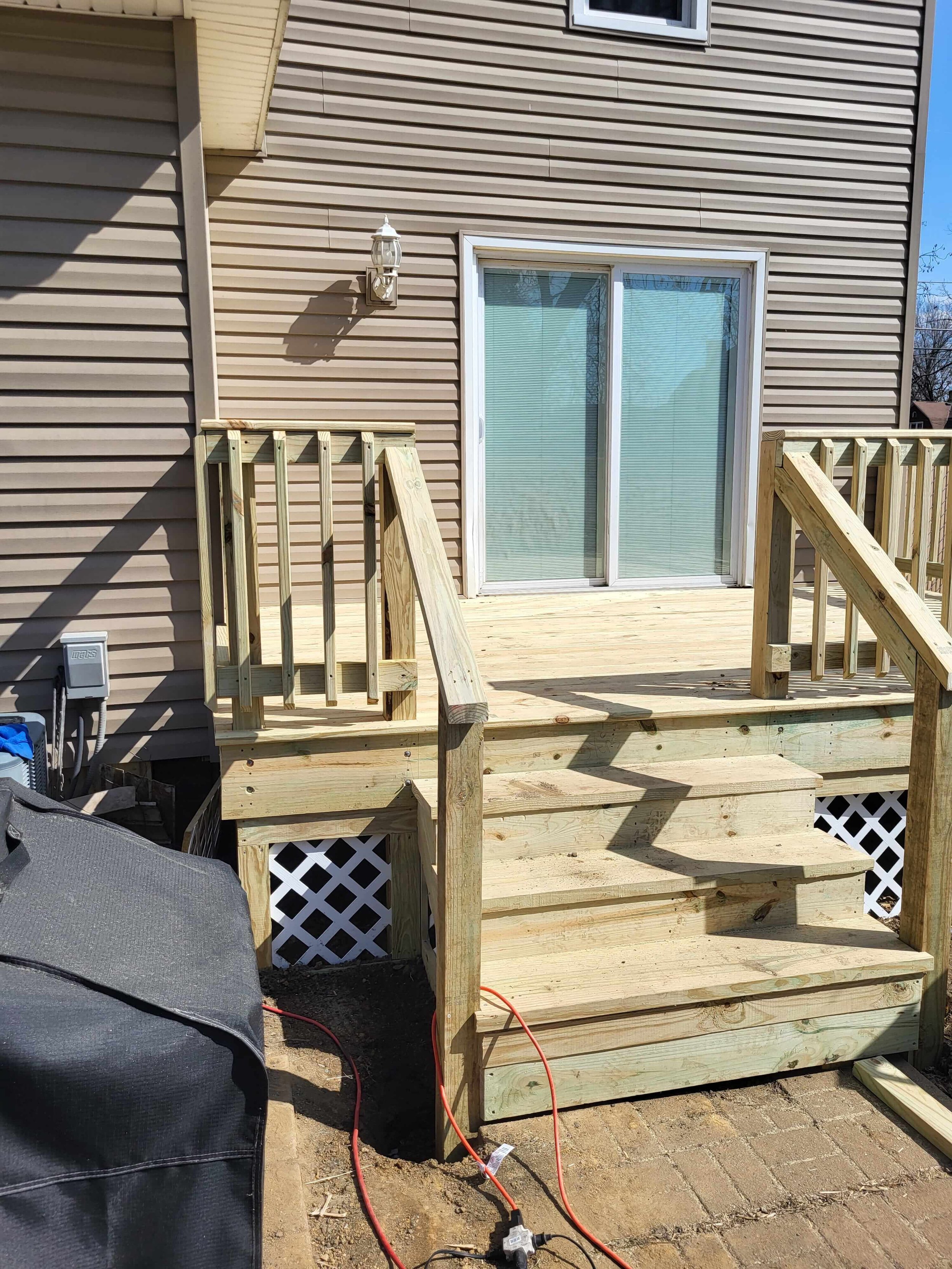 Aging deck rebuilt with new framing, stairs, and railings for a safer front entrance.