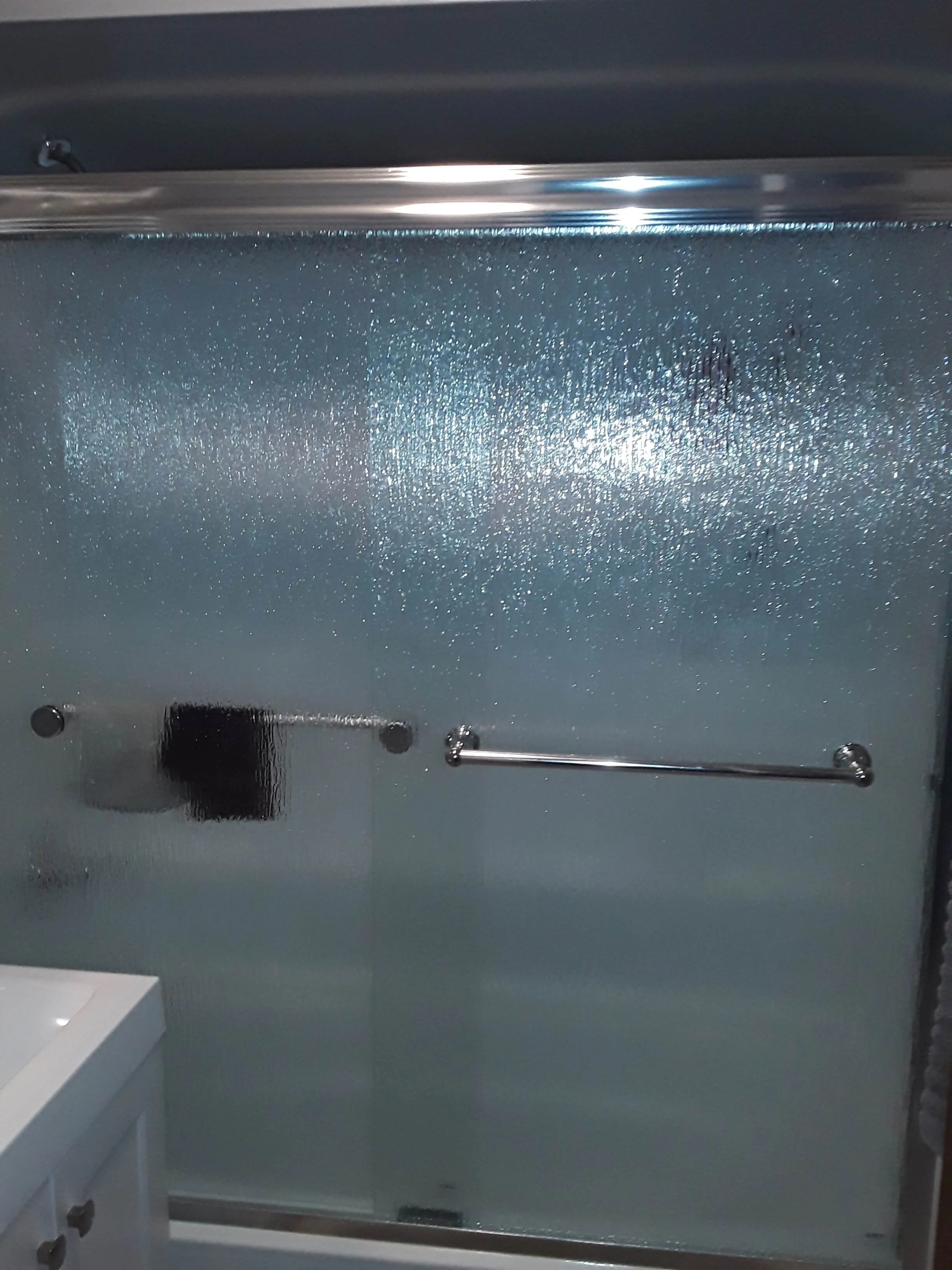 Sliding frosted glass privacy shower doors installed in small bathroom remodel